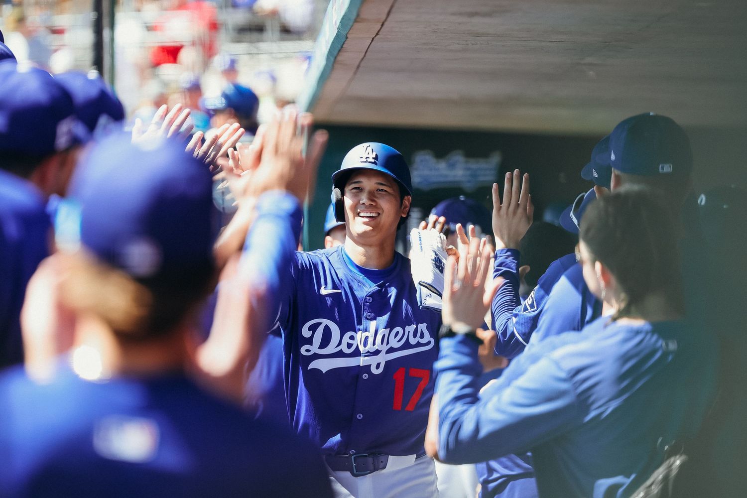 Los Angeles Dodgers player number 17 celebrating with teammates in the dugout with high-fives.