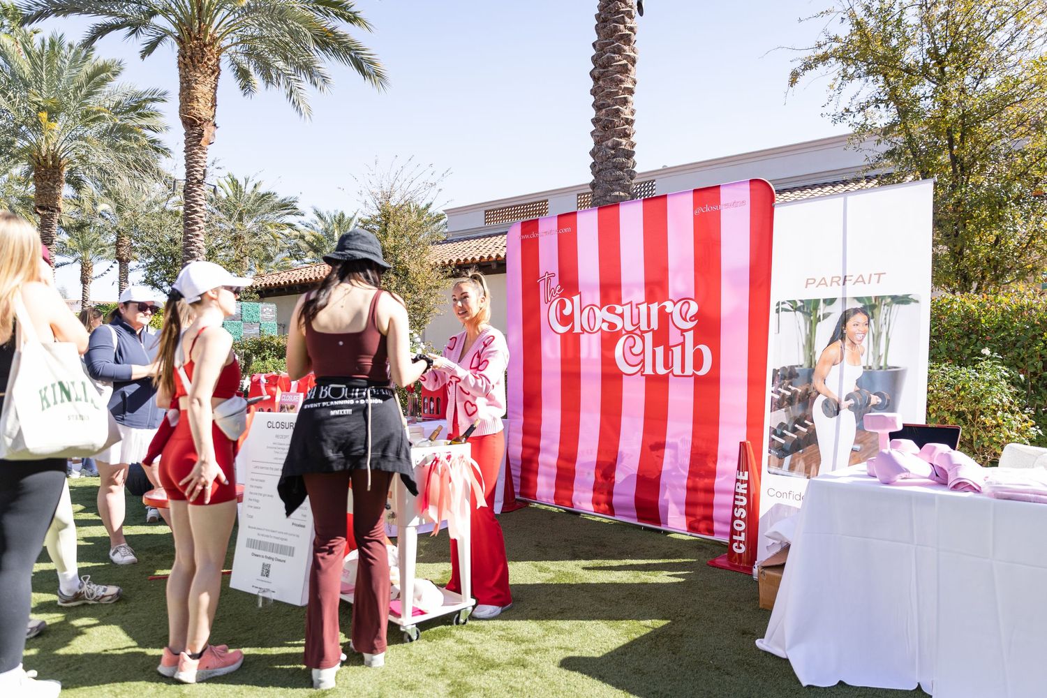Attendees gather at the Closure Club booth with red and white striped backdrop at an outdoor event.