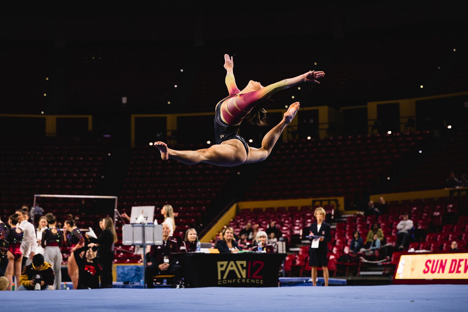 ASU Sun Devils gymnast performs a dynamic floor exercise leap at Desert Financial Arena.