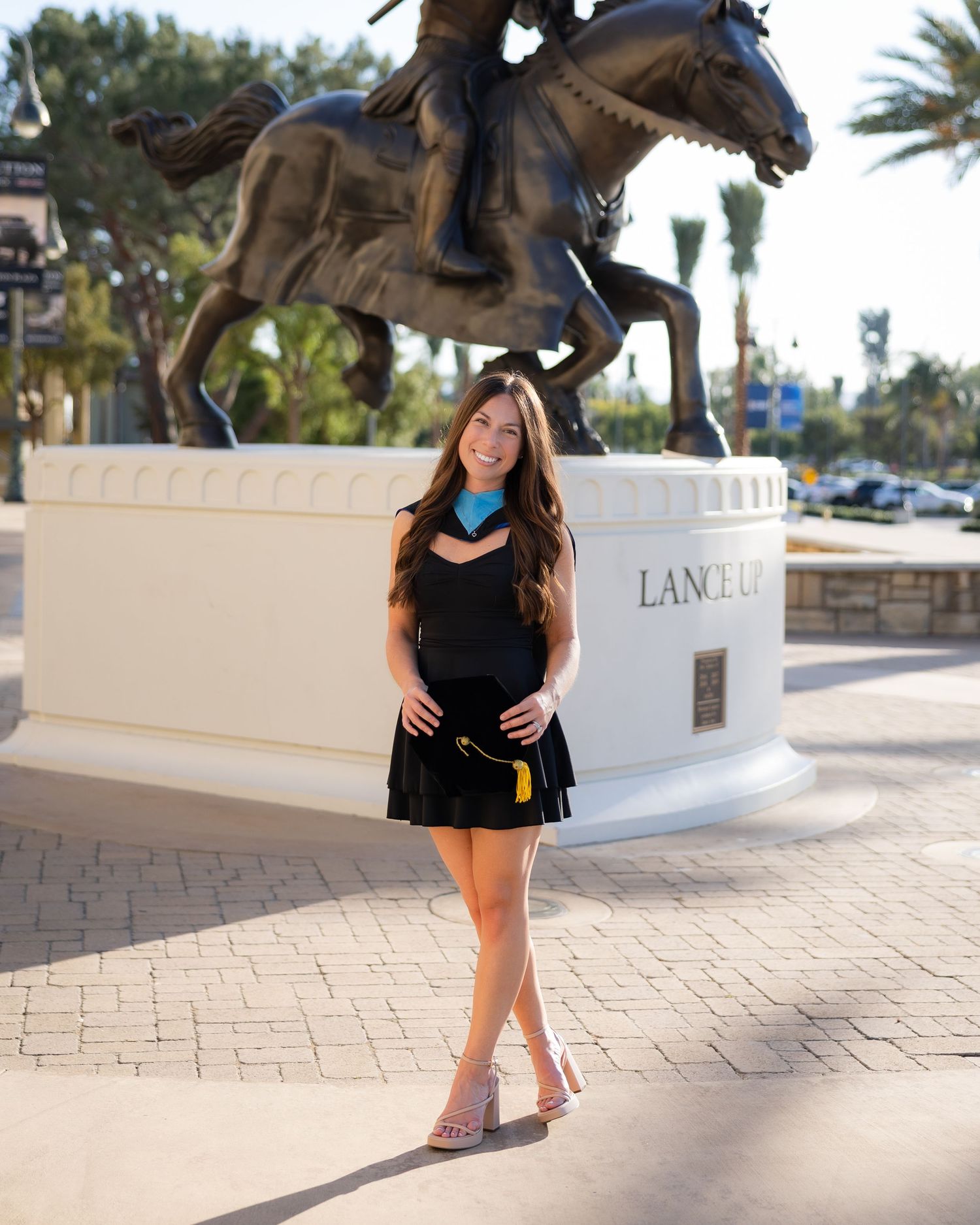 Young woman in black outfit poses confidently near Lance Uppercut bronze equestrian statue outdoors.