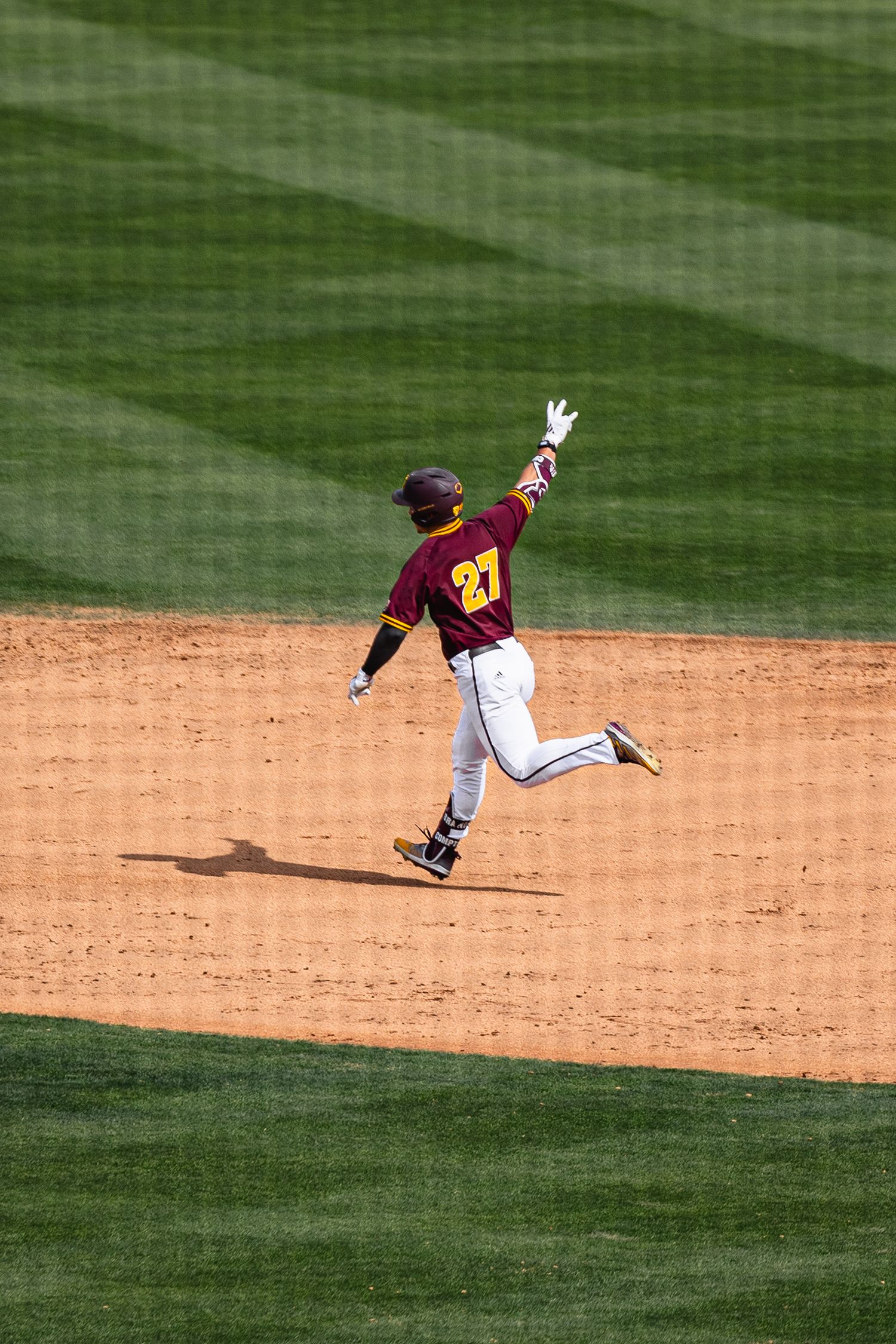 Arizona State Sun Devils baseball player #27 rounds second base celebrating during a college baseball game.