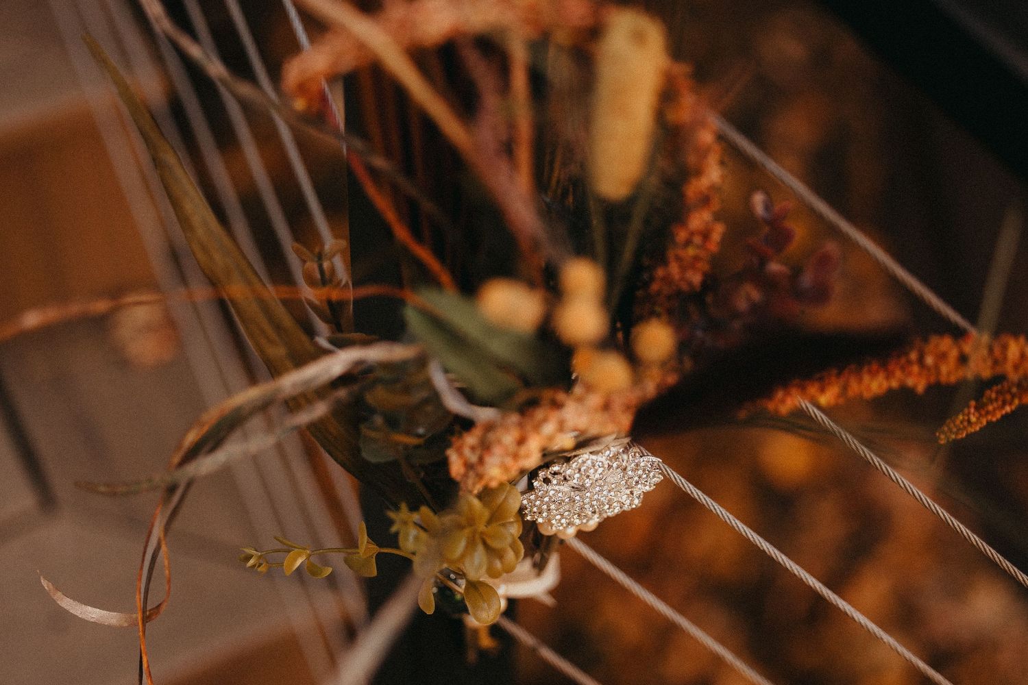 Rustic boho wedding boutonniere with dried flowers and lace detail on harp strings.