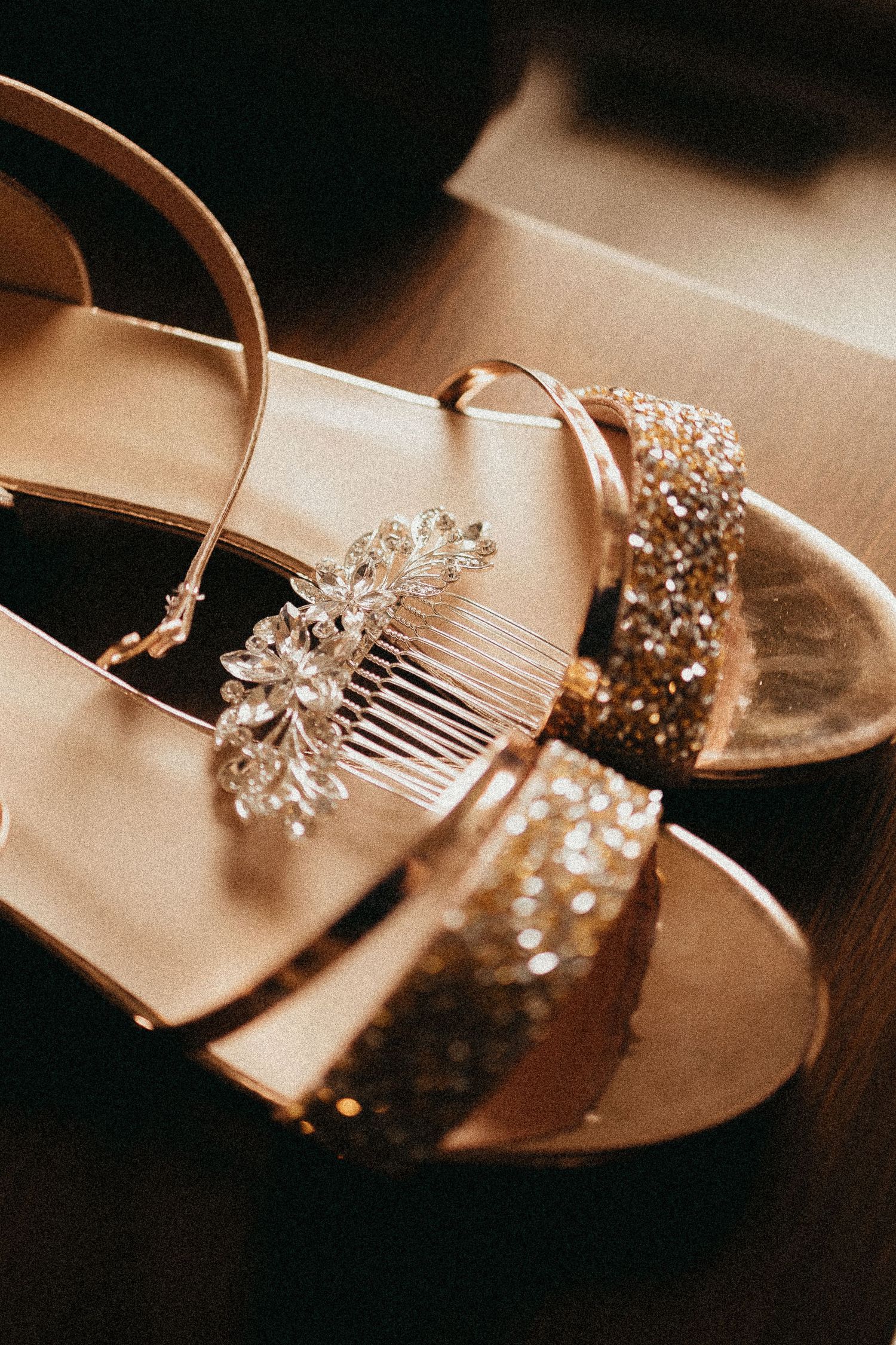Sparkling gold glitter bridal sandals with crystal hair comb accessory on dark surface.