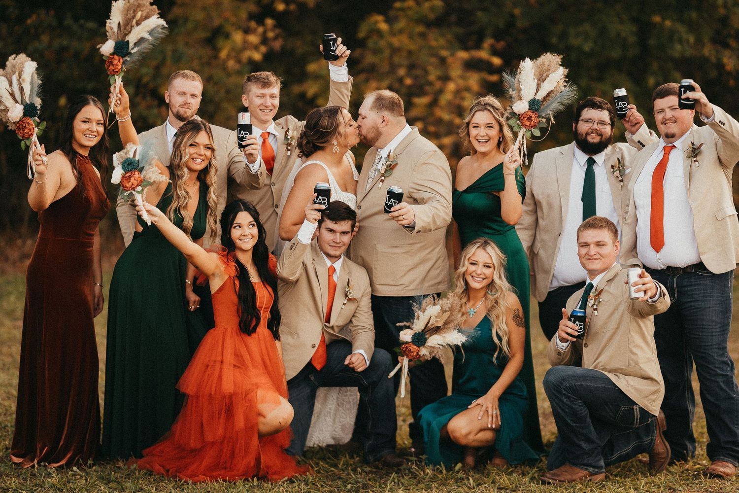 Wedding party in fall colors celebrating outdoors with drinks, bridesmaids in green and orange.