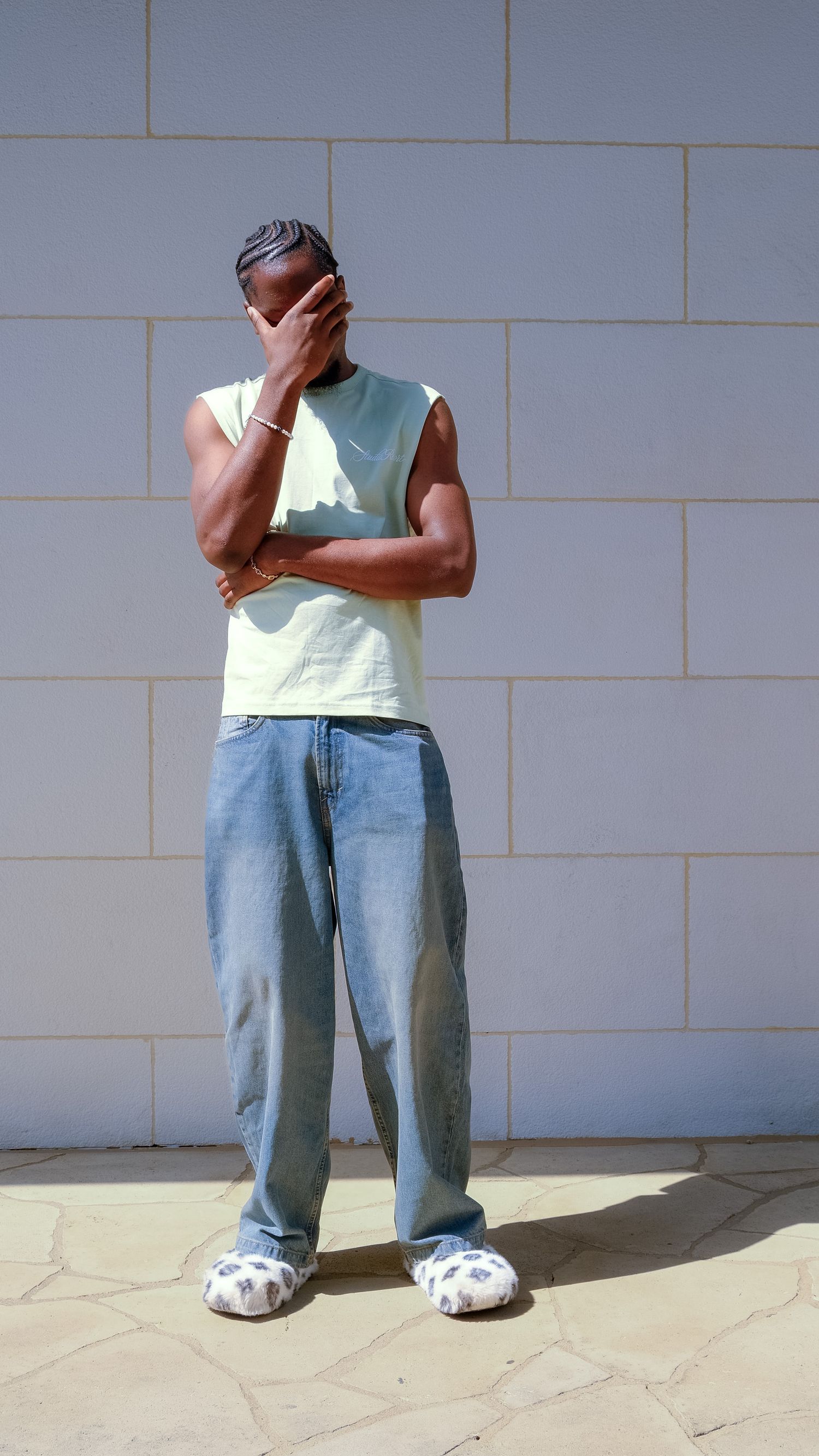 Man in a white top and jeans posing outdoors in a thoughtful stance