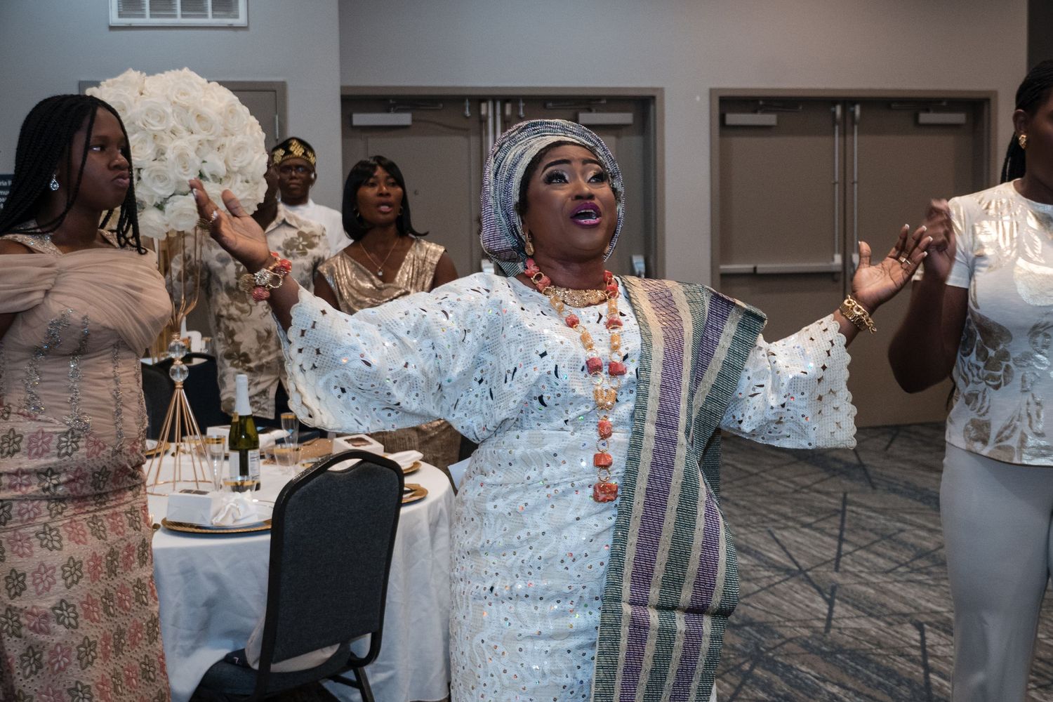 Woman in white traditional attire dancing joyfully with arms raised at a celebration