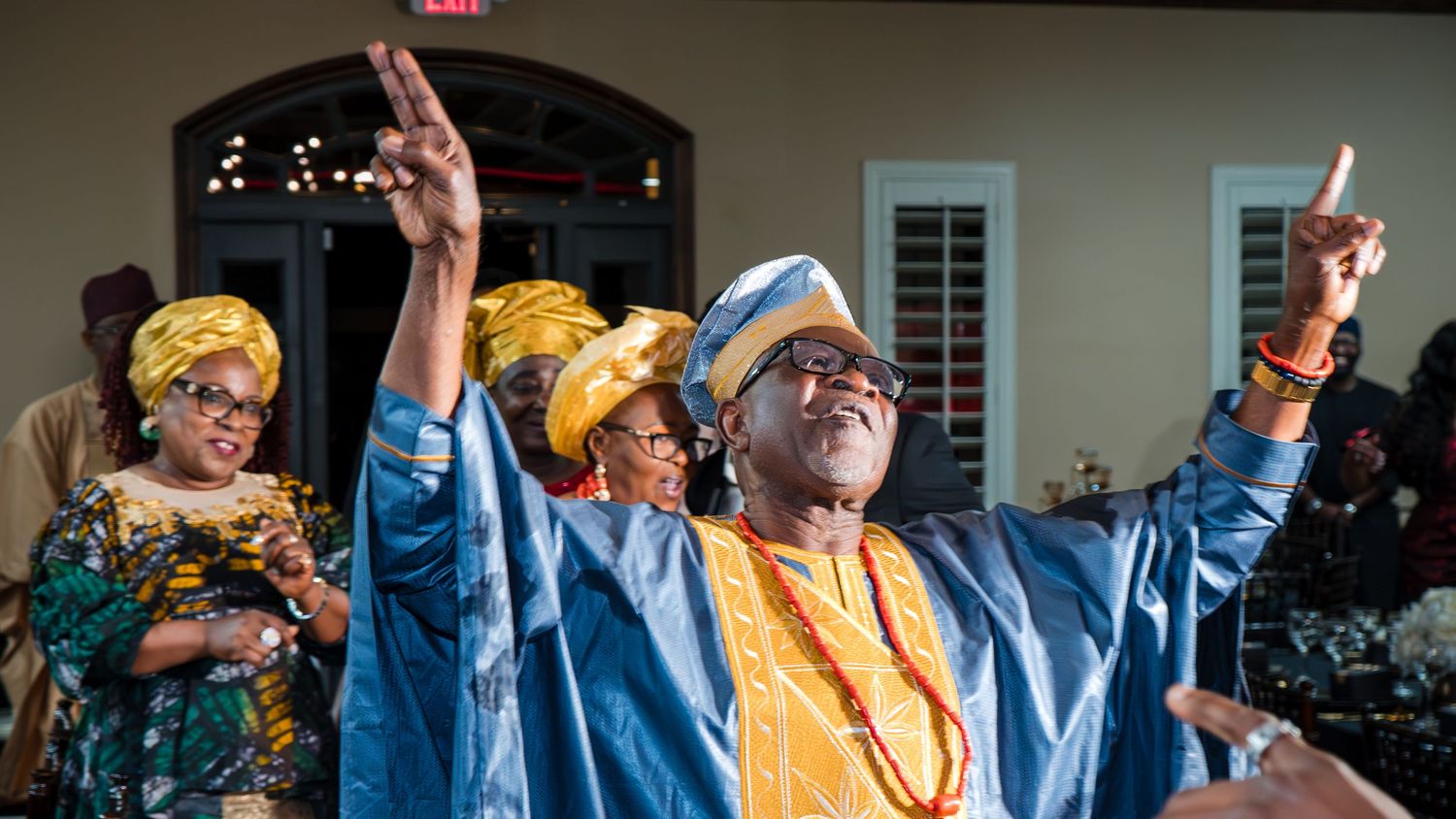 Guests in colorful traditional attire dancing and celebrating at a 70th birthday party