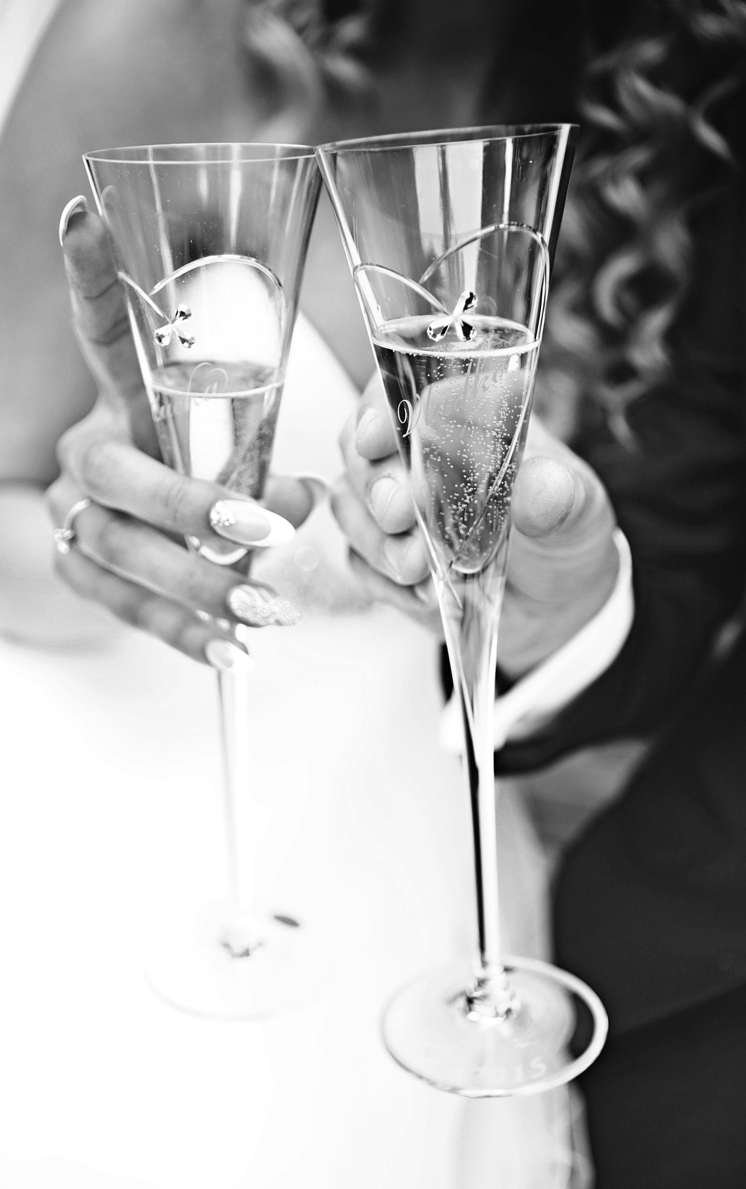 Black and white close-up of hands toasting with champagne glasses