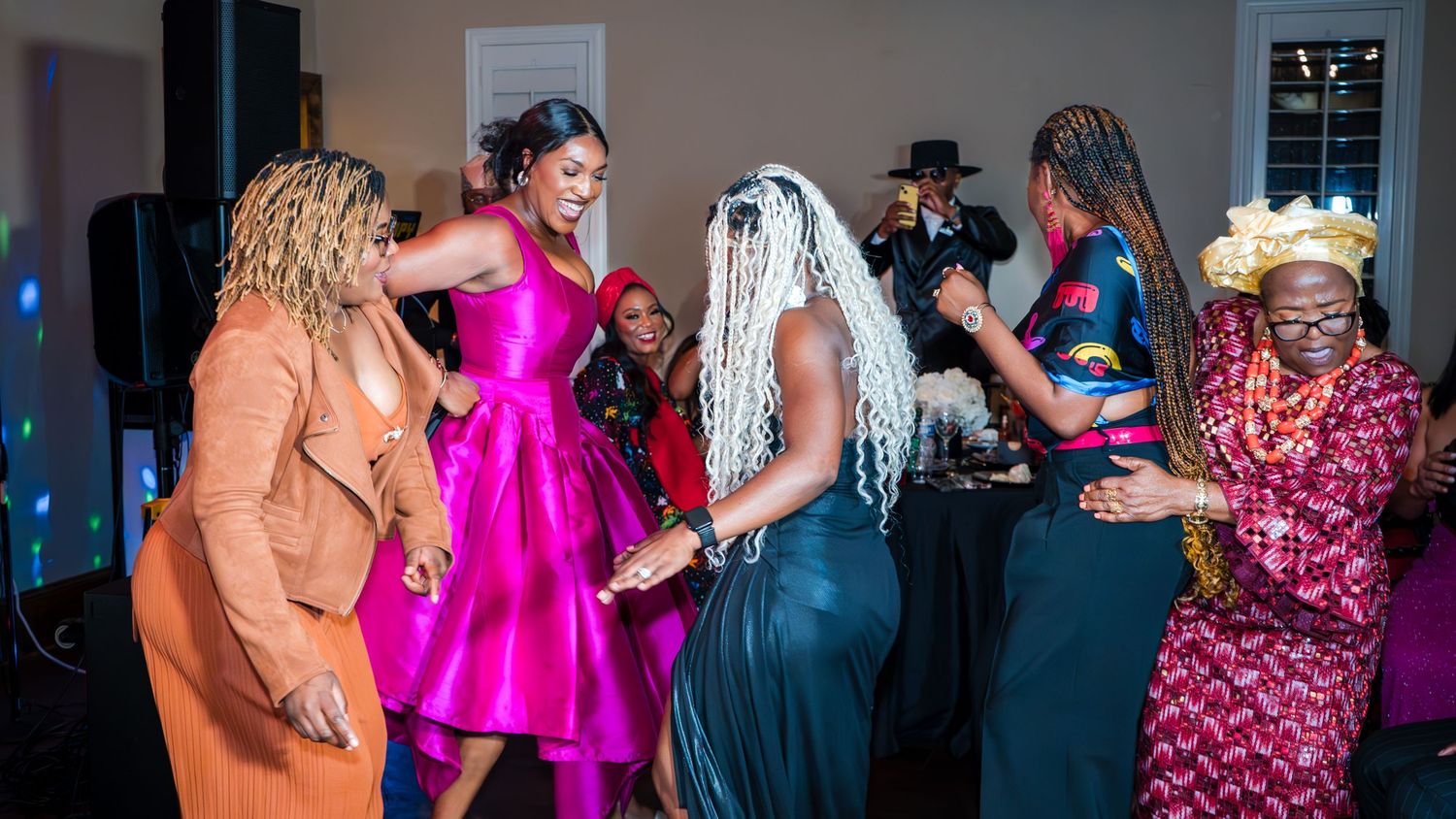 Group of women dancing joyfully together at an indoor birthday celebration
