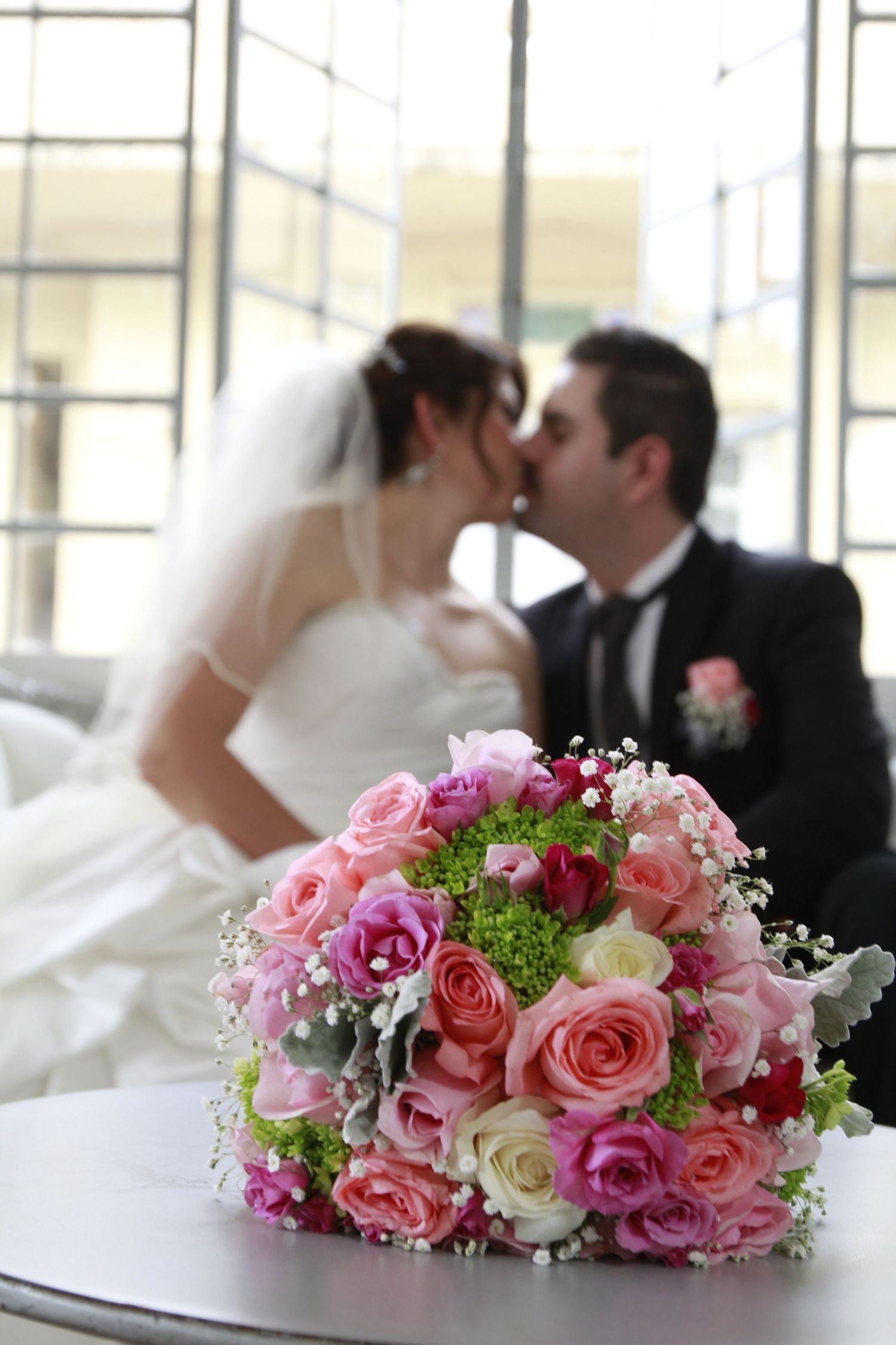 Bride and groom sharing a kiss with a colorful bouquet in the foreground