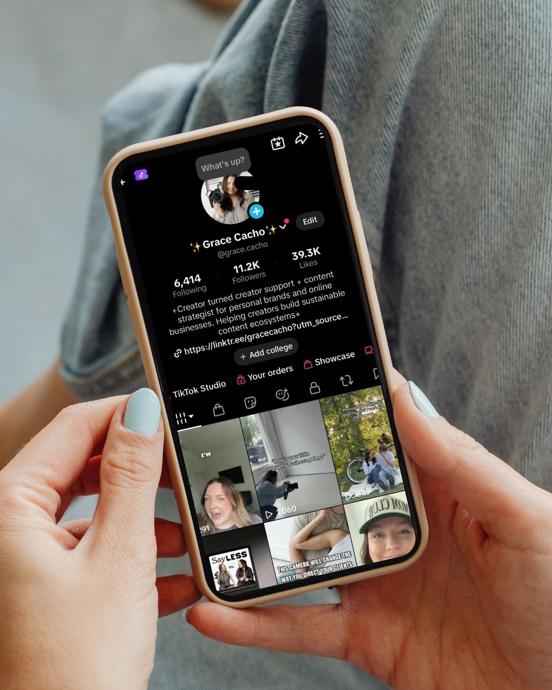 Hands holding iPhone displaying TikTok profile page with 39.3K followers in natural light.