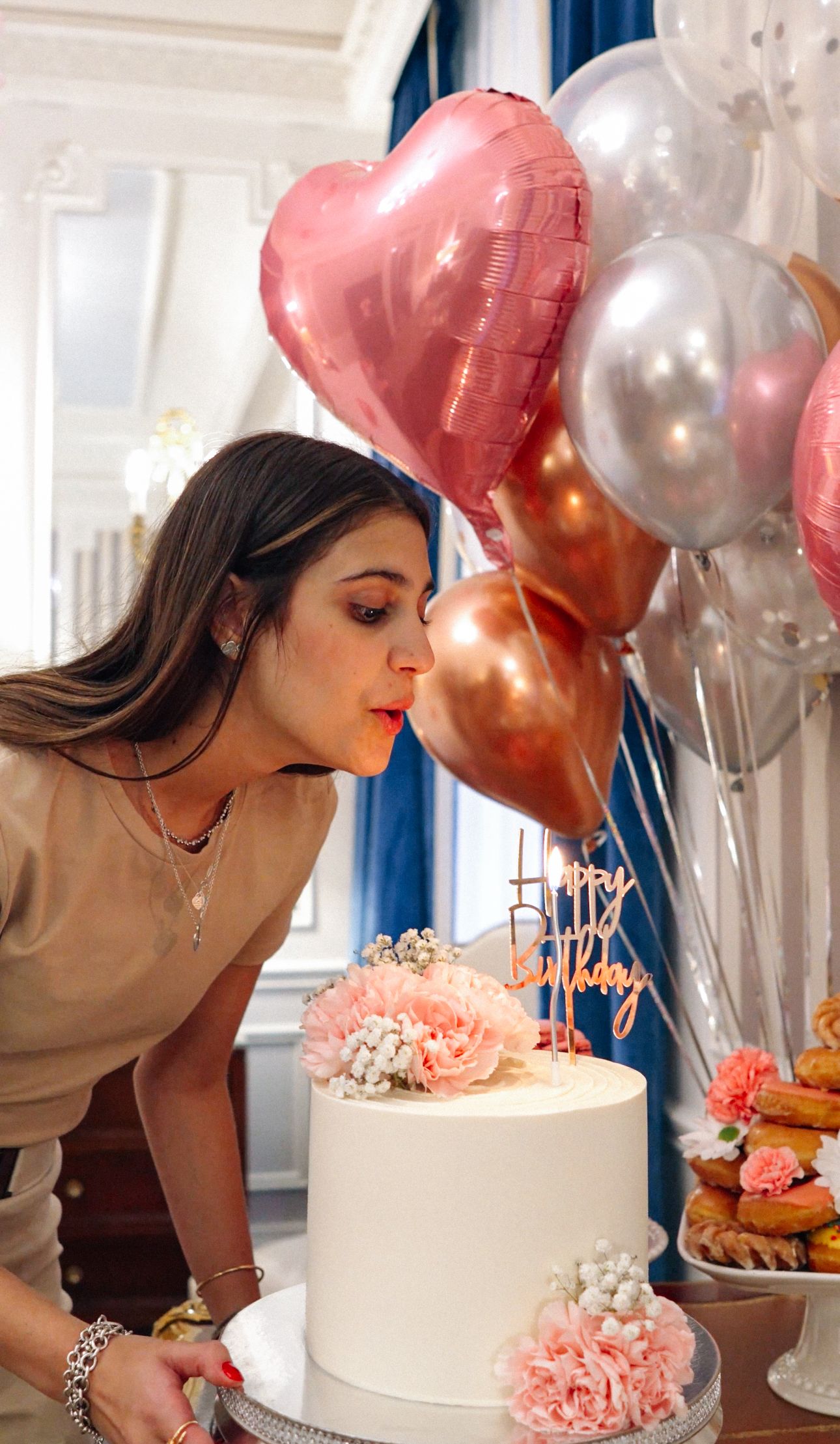 A sequence of photos showing someone blowing out birthday candles on a white cake surrounded by pink and silver balloons.