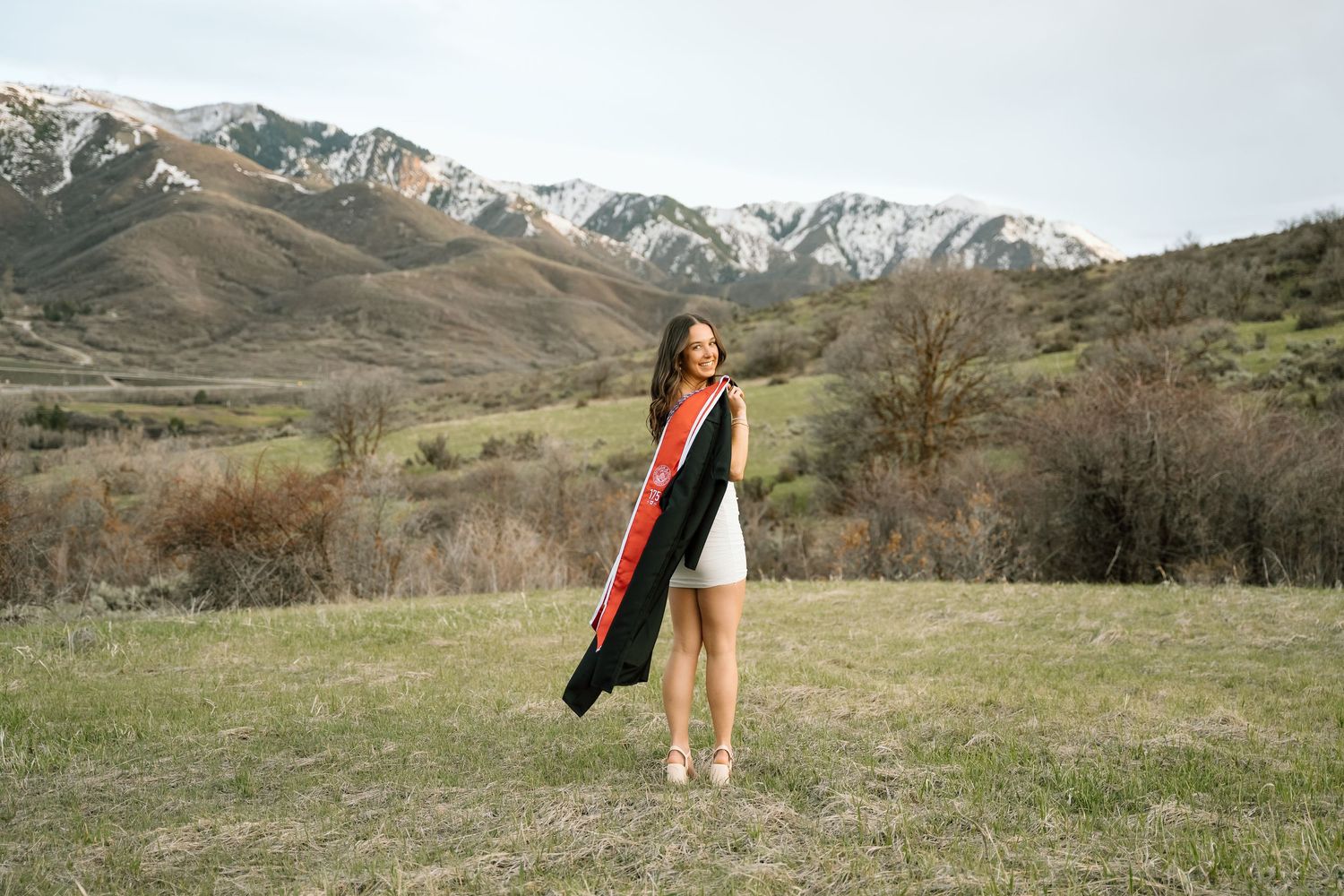 A University of Utah graduate with her gown and stol in the mountains