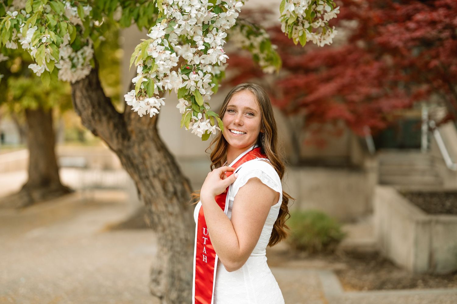 A University of Utah graduate in front of some Spring cherry blossoms