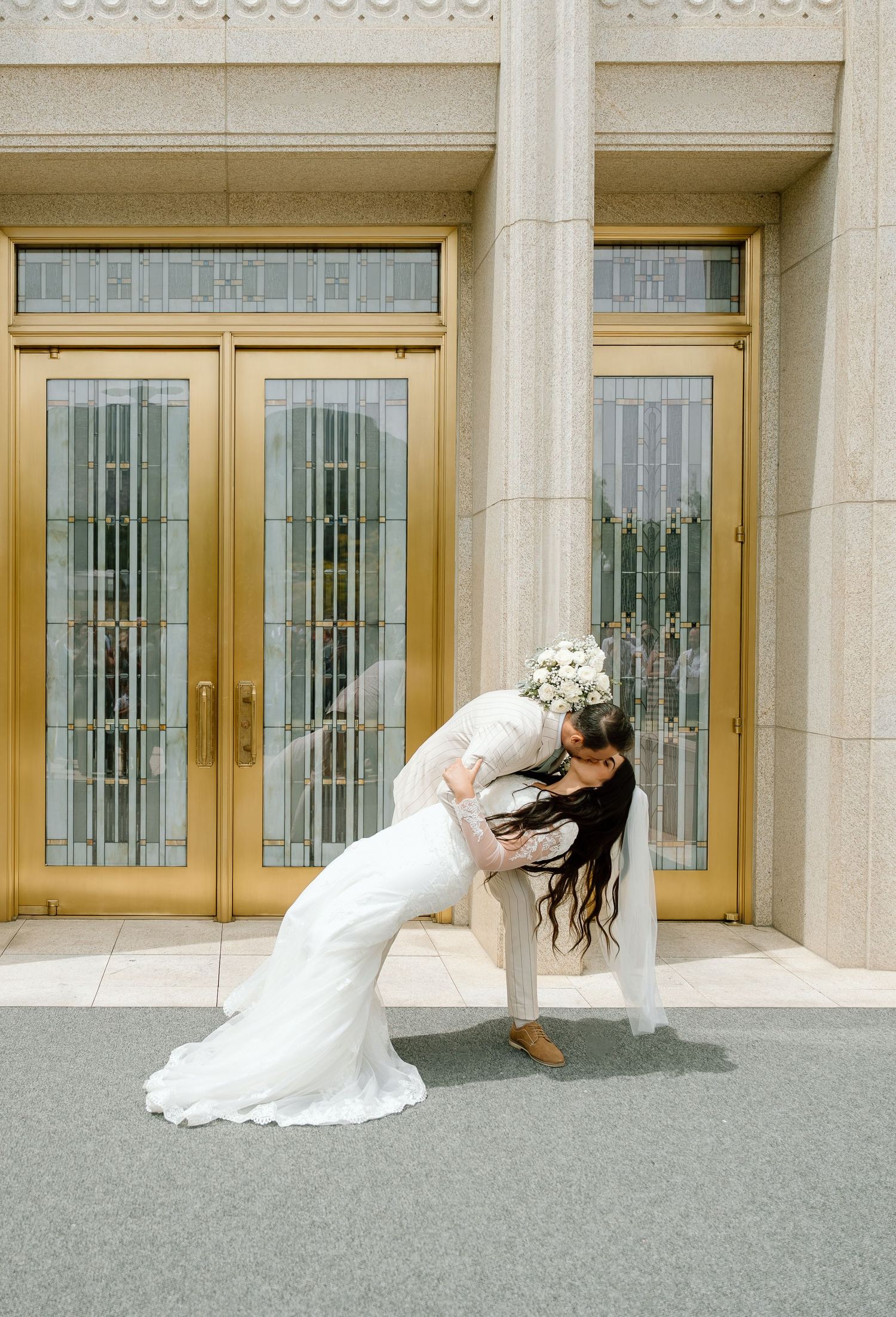 A bride and groom doing a dip kiss as they exit the Ogden, Utah Temple