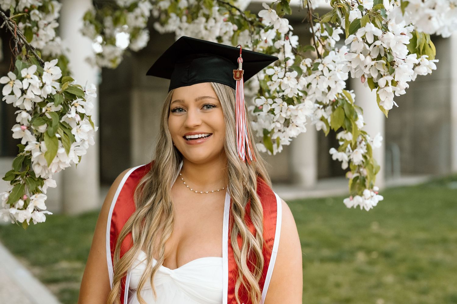 A University of Utah graduate in front of the Spring blossoms at the University of Utah