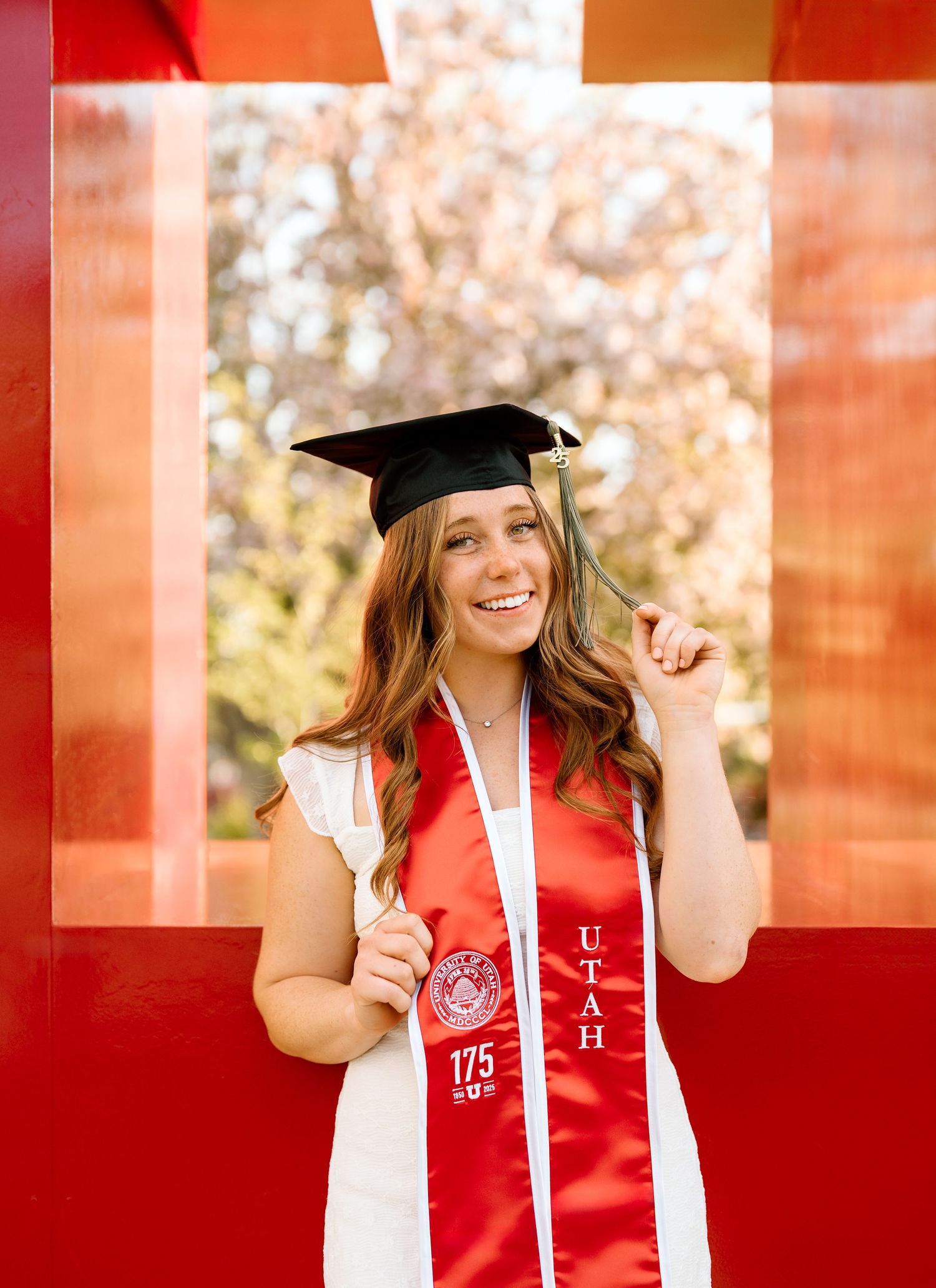 A University of Utah graduate in front of the red block U at the University of Utah