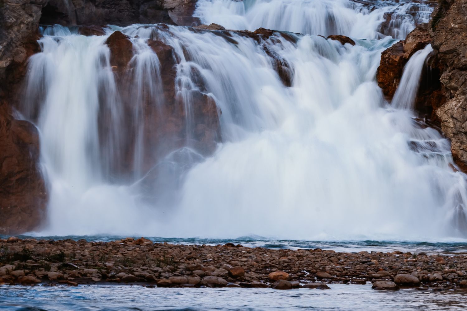 Multiple streams of white water flowing over rocky ledges creating a dramatic waterfall.