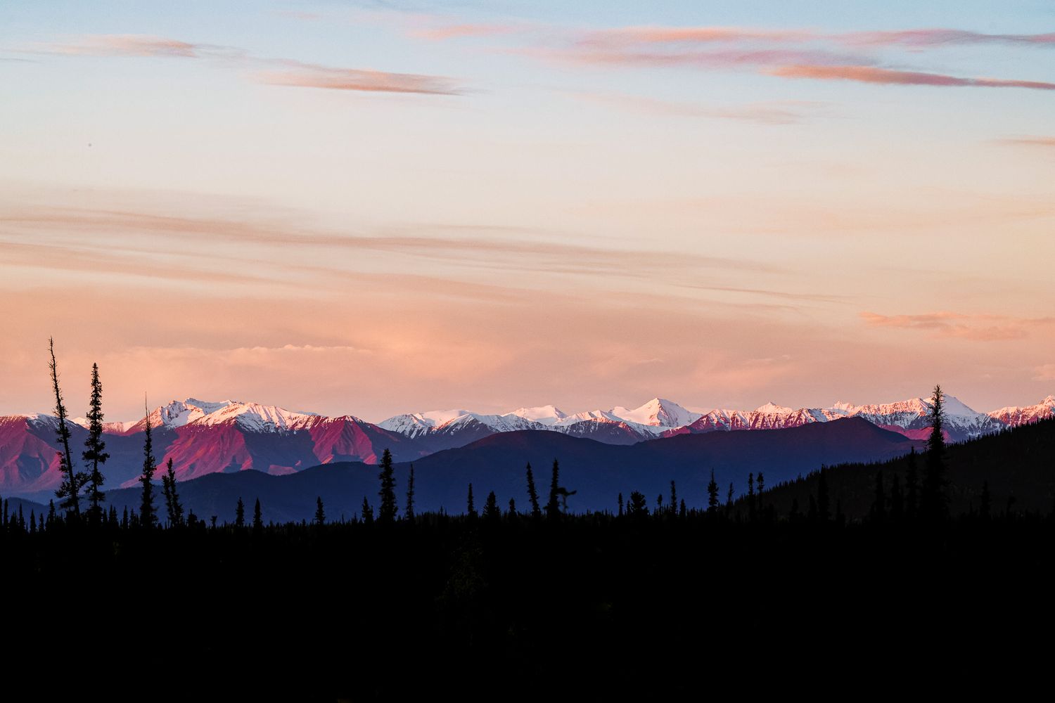Mountain range silhouetted against a pink and purple sunset sky.