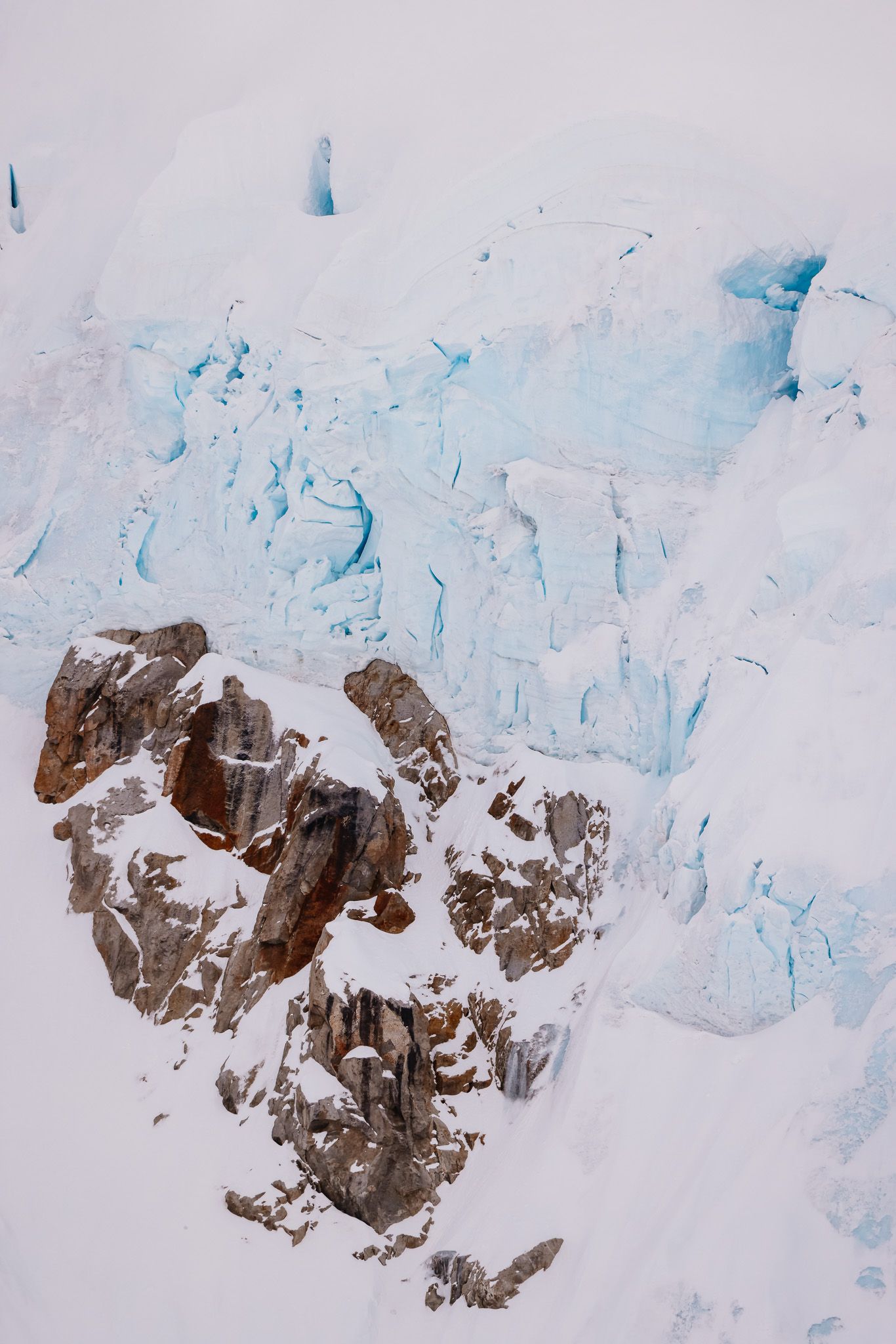 Dramatic glacier face with exposed rock formations and blue ice walls.
