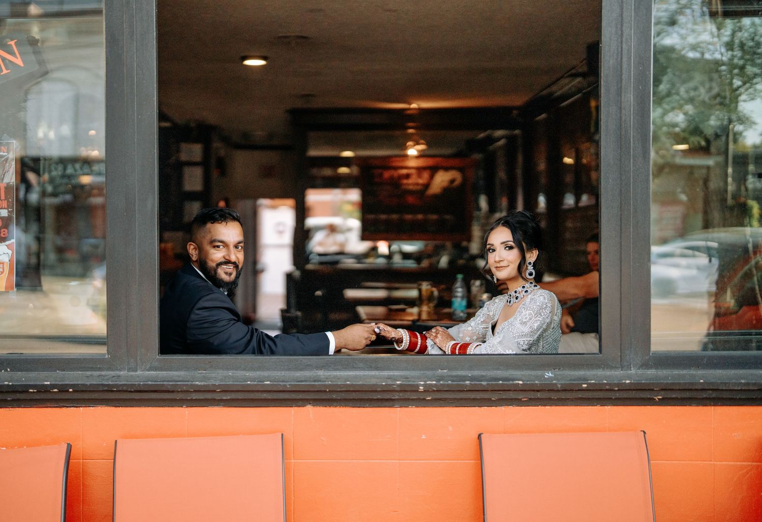 Two people sit at a restaurant booth by a window, enjoying drinks together in a warm, cozy atmosphere.