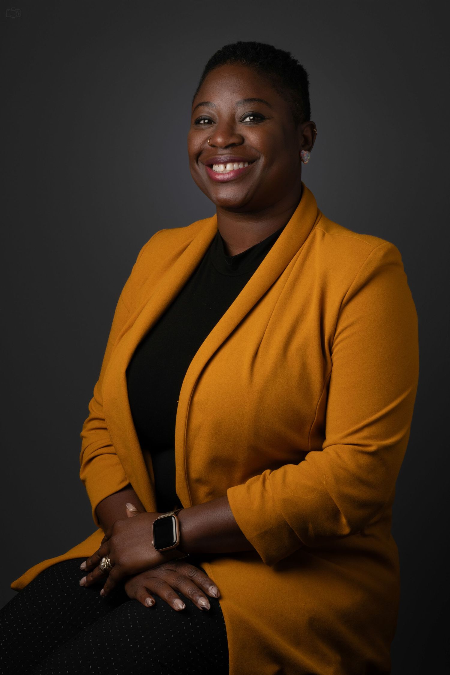 Studio portrait of a person wearing a vibrant yellow blazer over black attire.