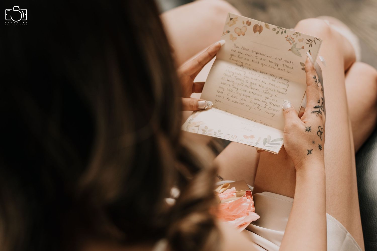 Hands holding a vintage-style letter or note card with decorative elements.