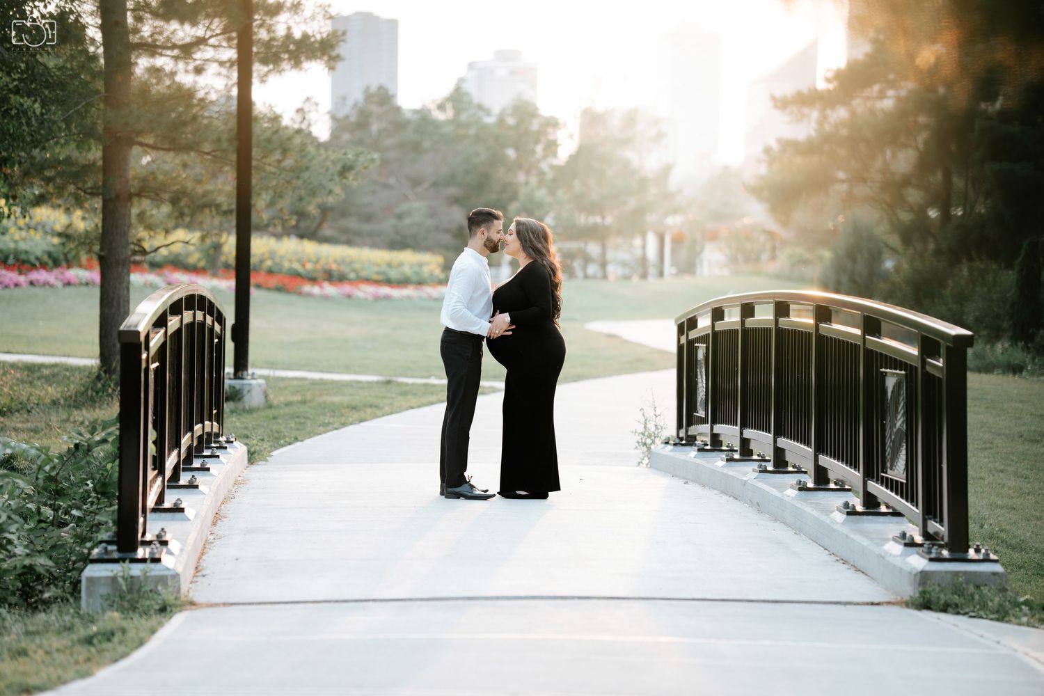 Couple sharing romantic moment on ornate bridge in park during sunset.