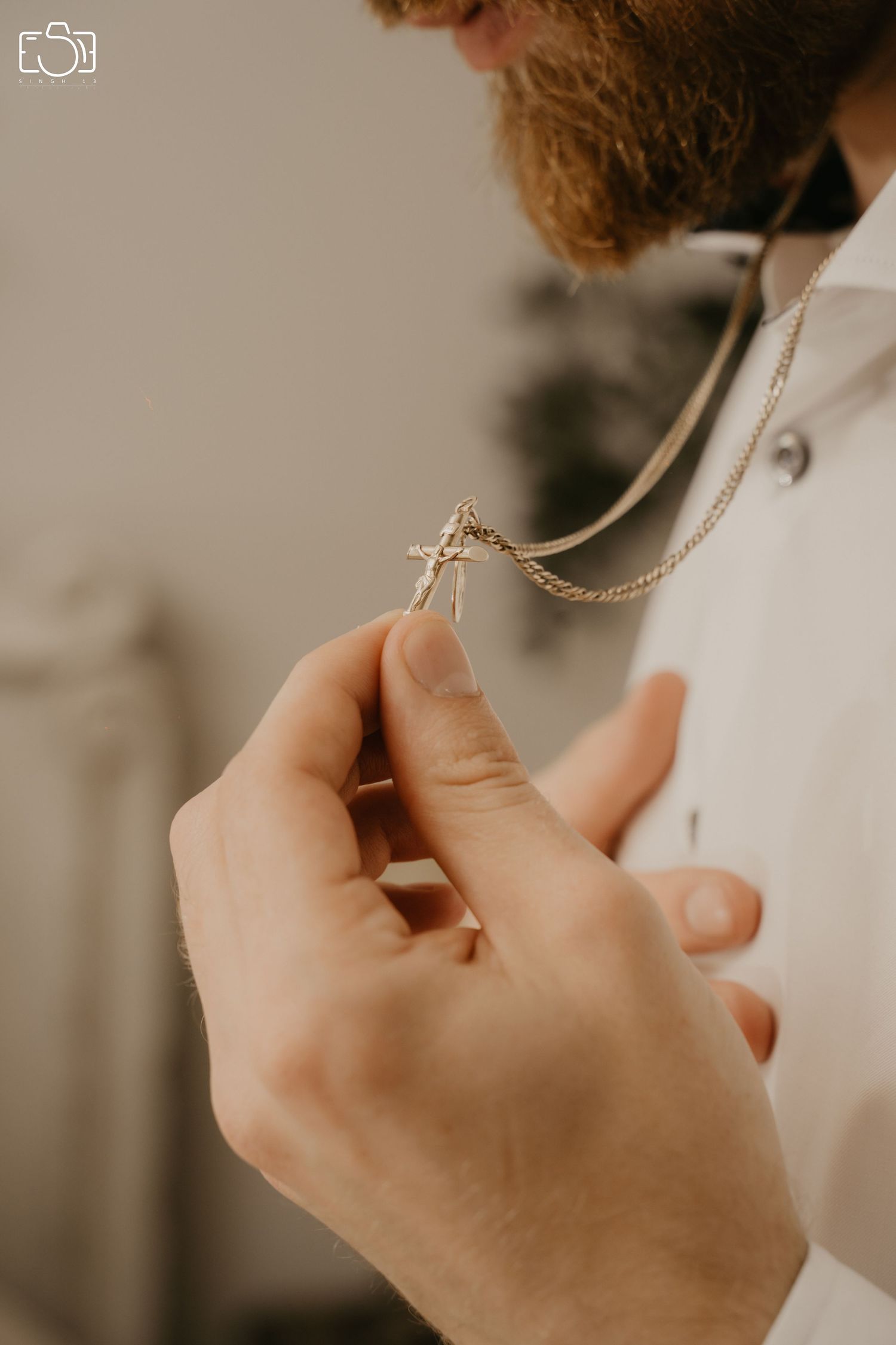 Close-up of hands holding a delicate gold necklace in warm natural light.