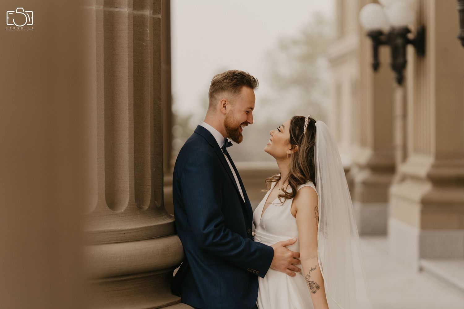 An intimate moment captured between a couple in formal attire against a classical building backdrop.