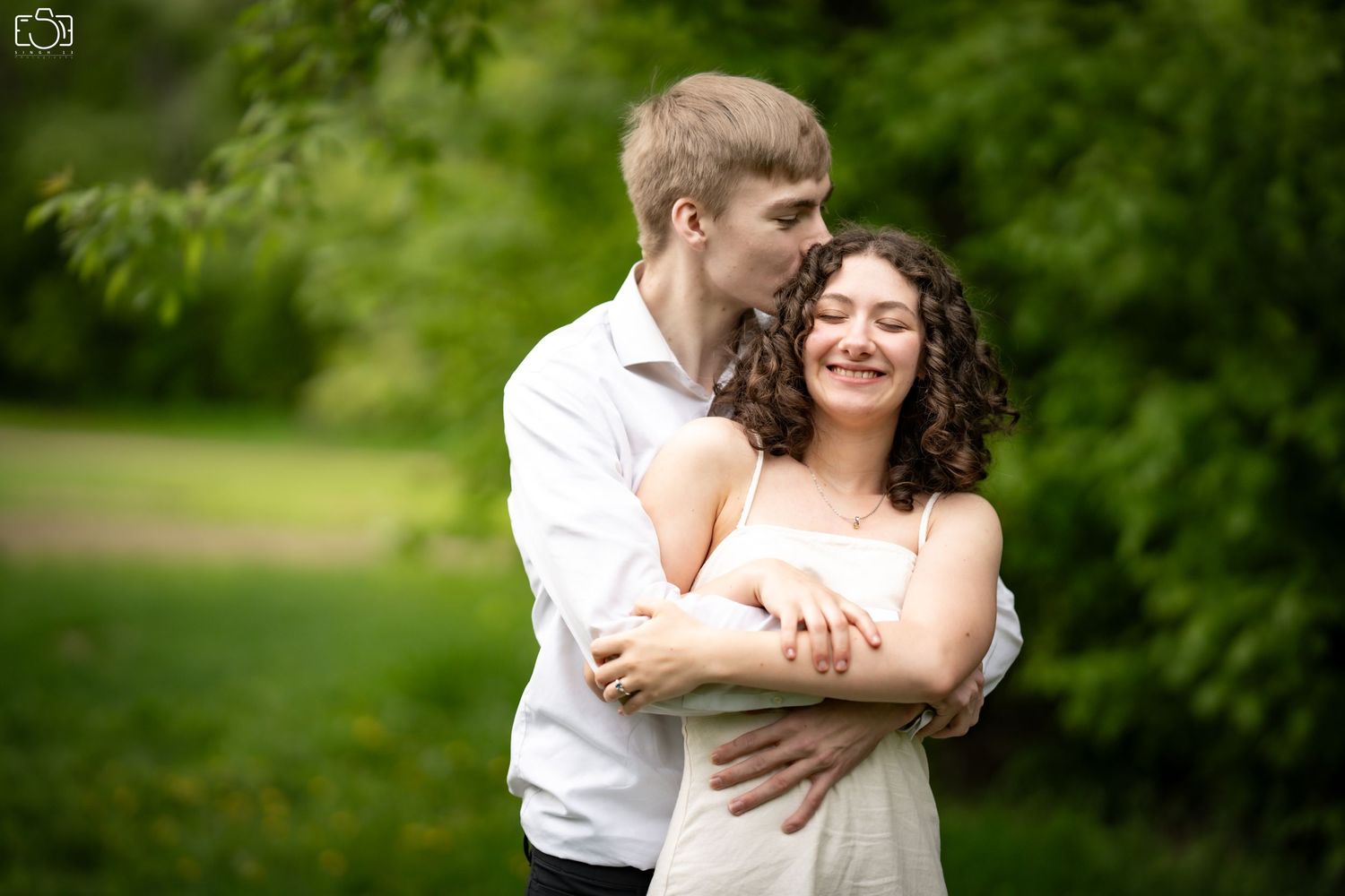 Couple shares tender moment in lush green garden setting during spring.