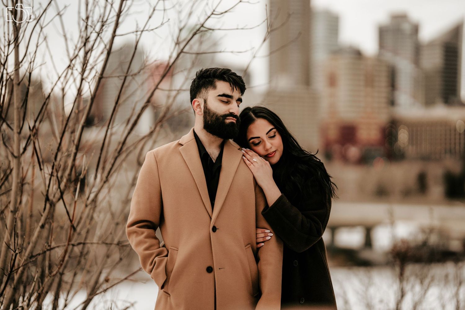 A romantic winter engagement photo with a city skyline backdrop.