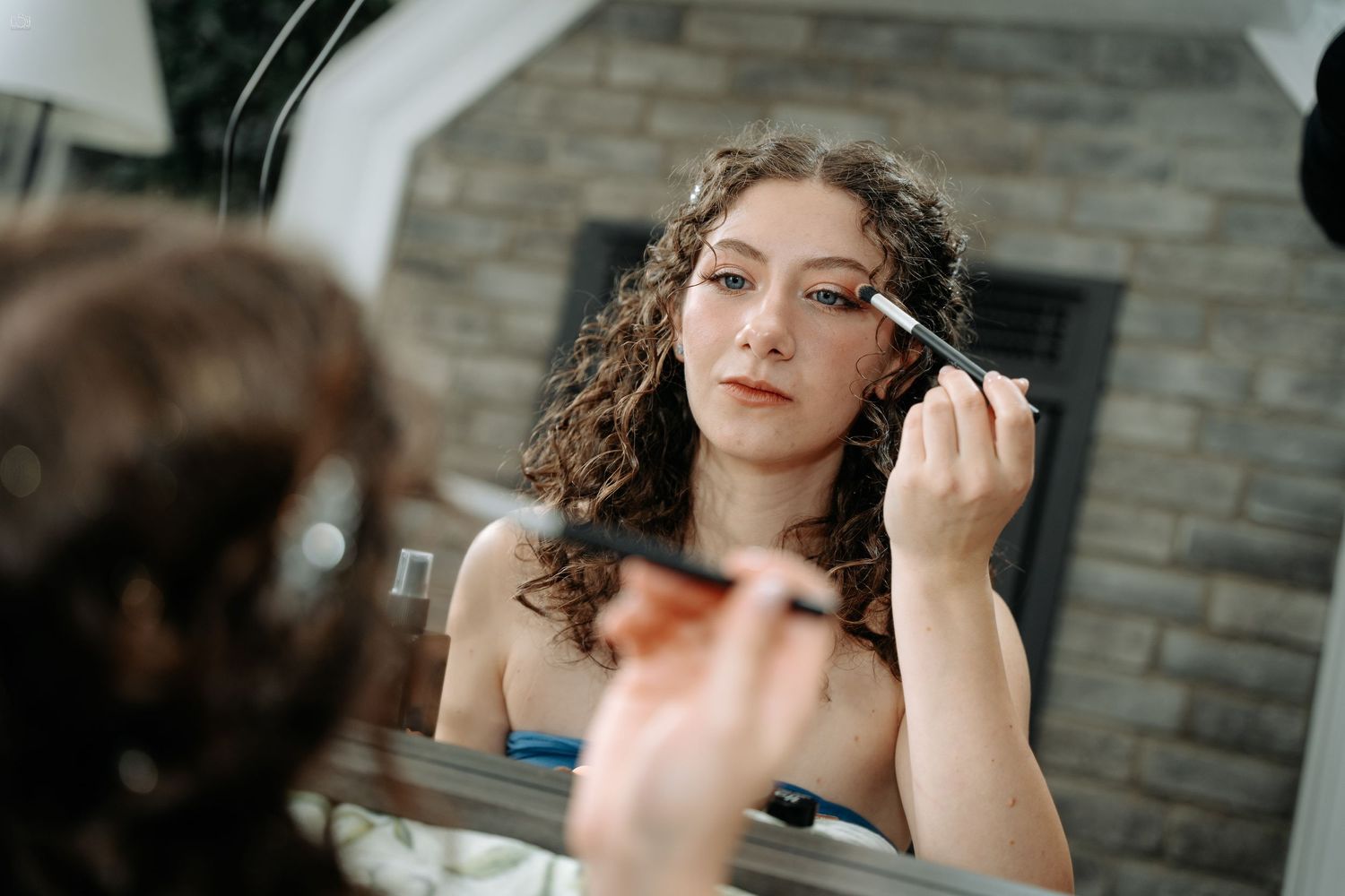 Getting ready scene with makeup application in mirror reflection.