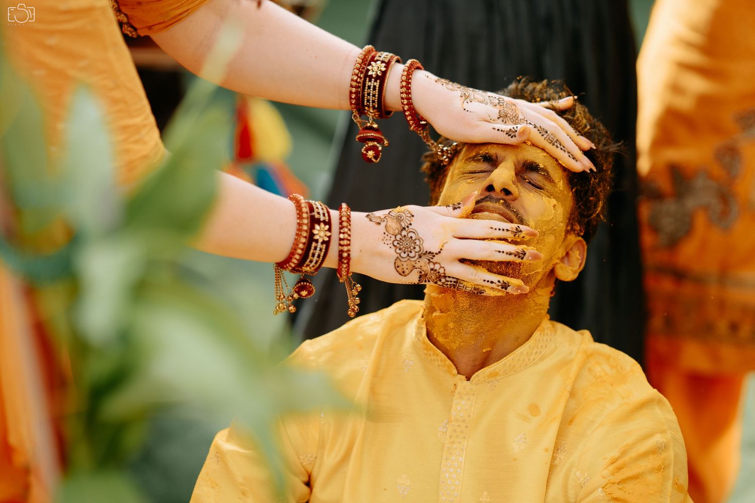 Traditional haldi ceremony with hands applying turmeric paste during pre-wedding ritual.