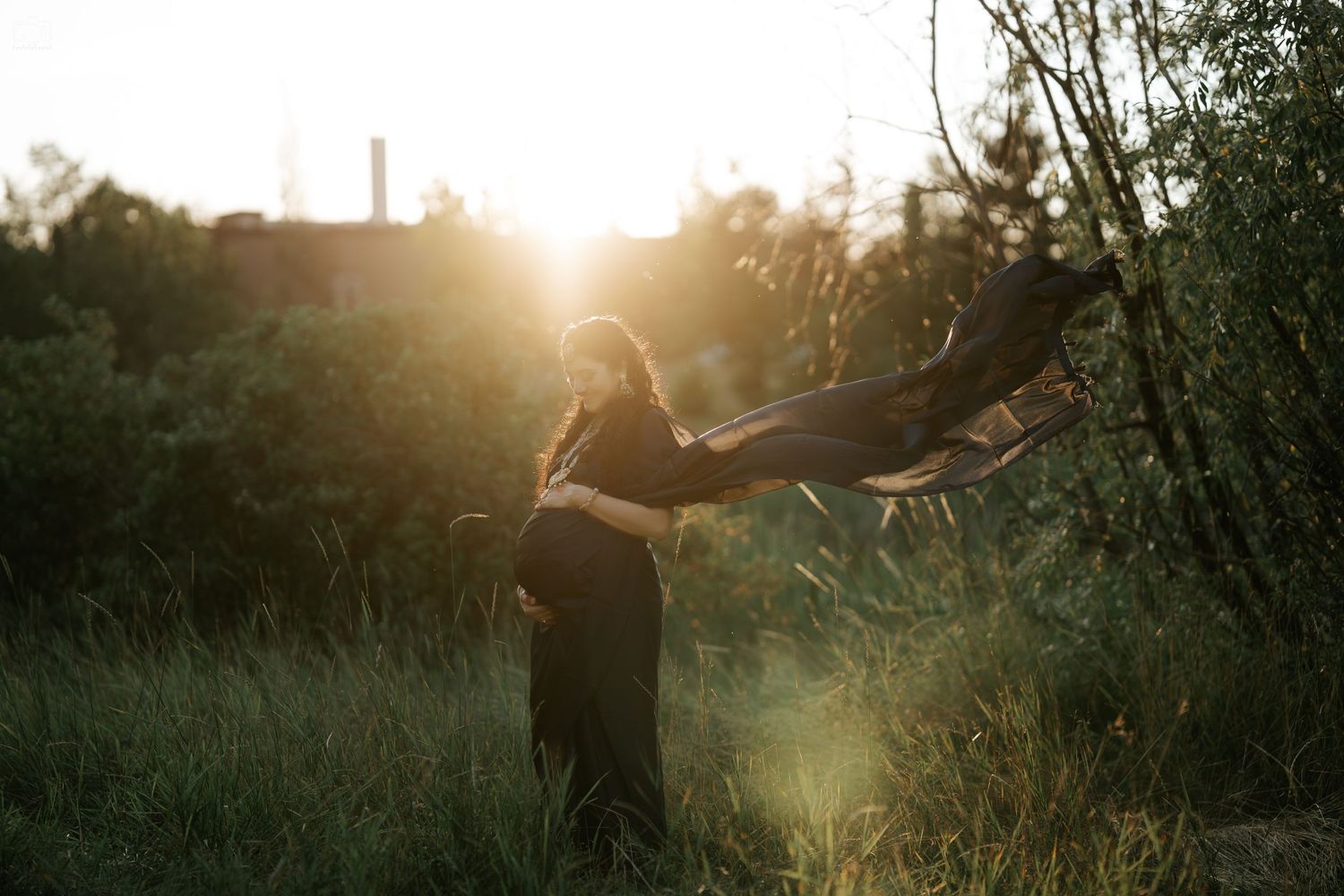 A silhouette of a person with flowing fabric against a golden sunset.