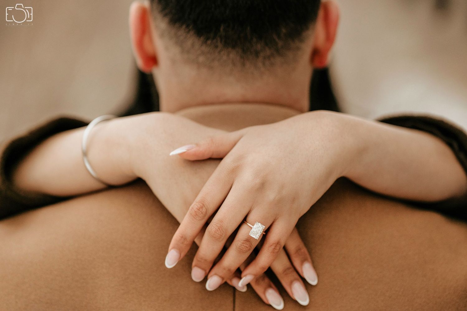 Close-up of hands embracing with an engagement ring on display.