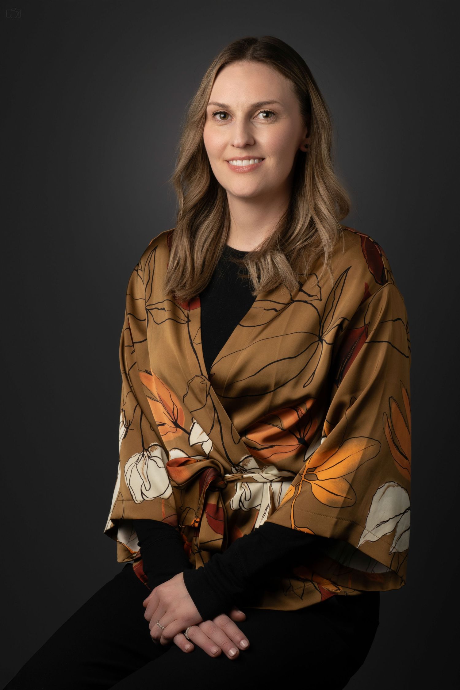 Portrait of a person wearing a floral print wrap jacket in brown and orange tones.