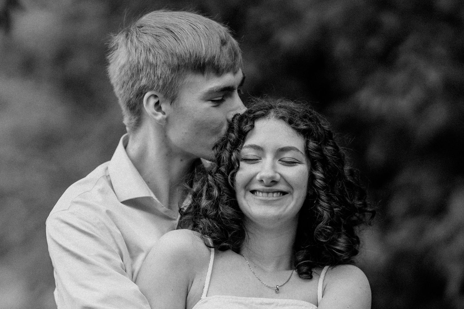 Black and white romantic portrait of a couple embracing outdoors.