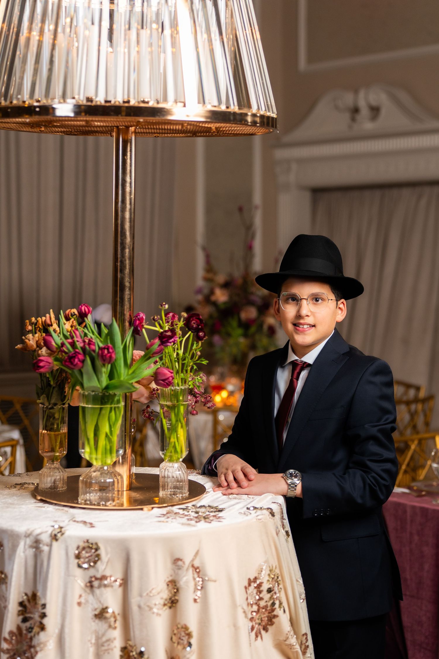 Elegant dining table setup with crystal lamp and tulip centerpiece in a formal banquet room.