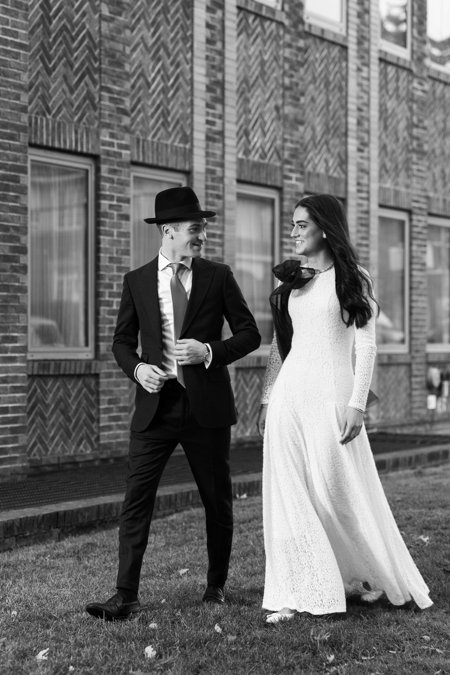 A playful black and white wedding photo sequence showing a couple dancing and twirling against a brick wall backdrop.