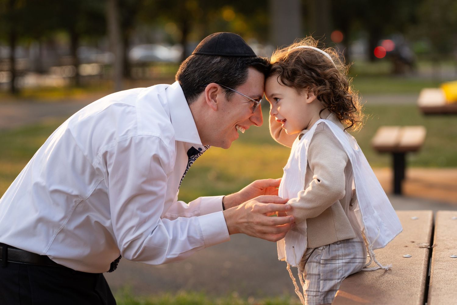 A tender moment between parent and child playing together in a park on a sunny afternoon.