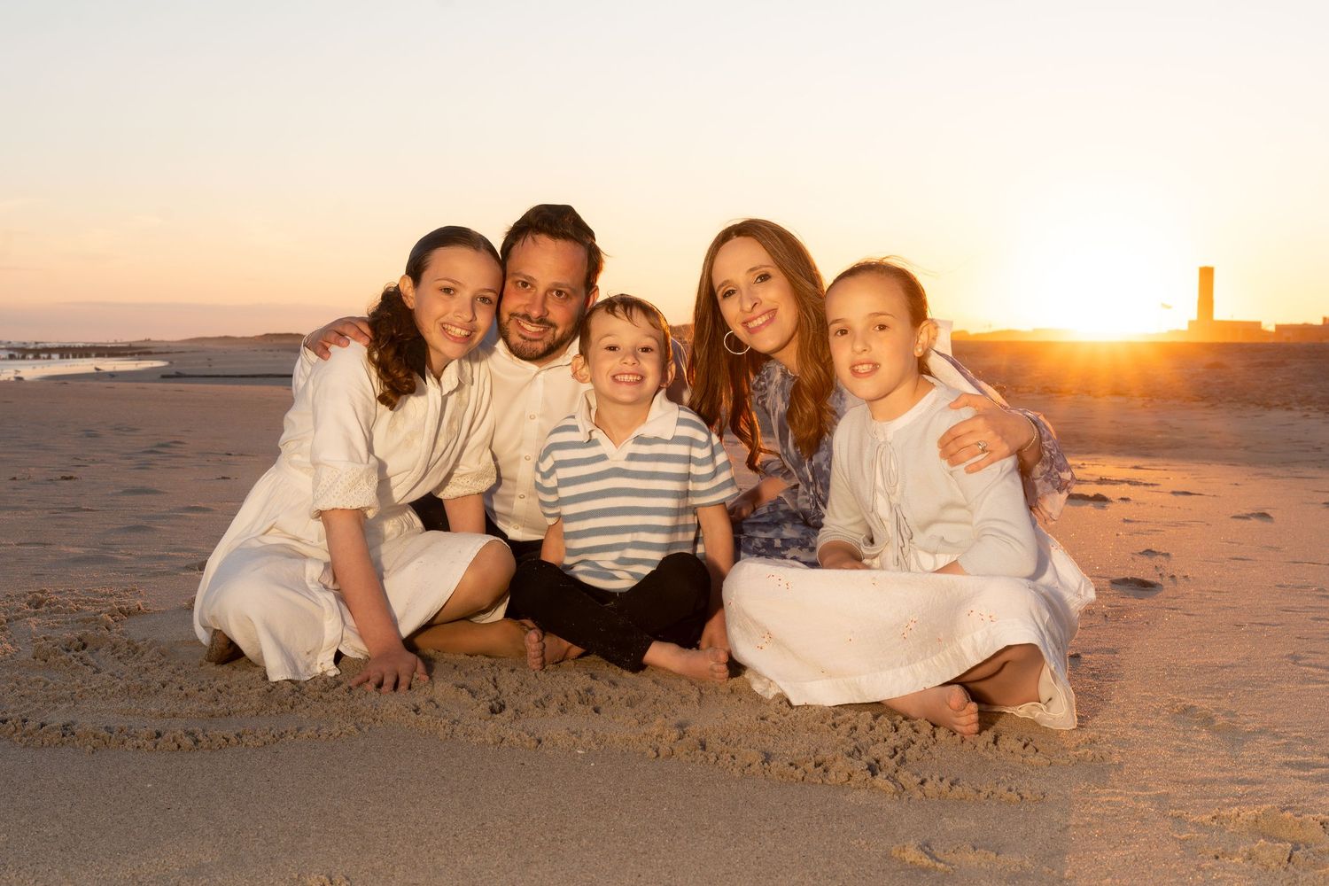 A group relaxes together on a sandy beach during golden hour sunset.