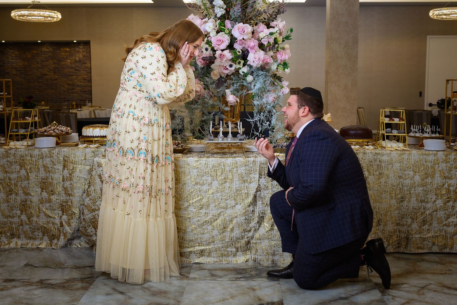 Special moment captured in an elegantly decorated indoor venue with stone walls and floral arrangements.