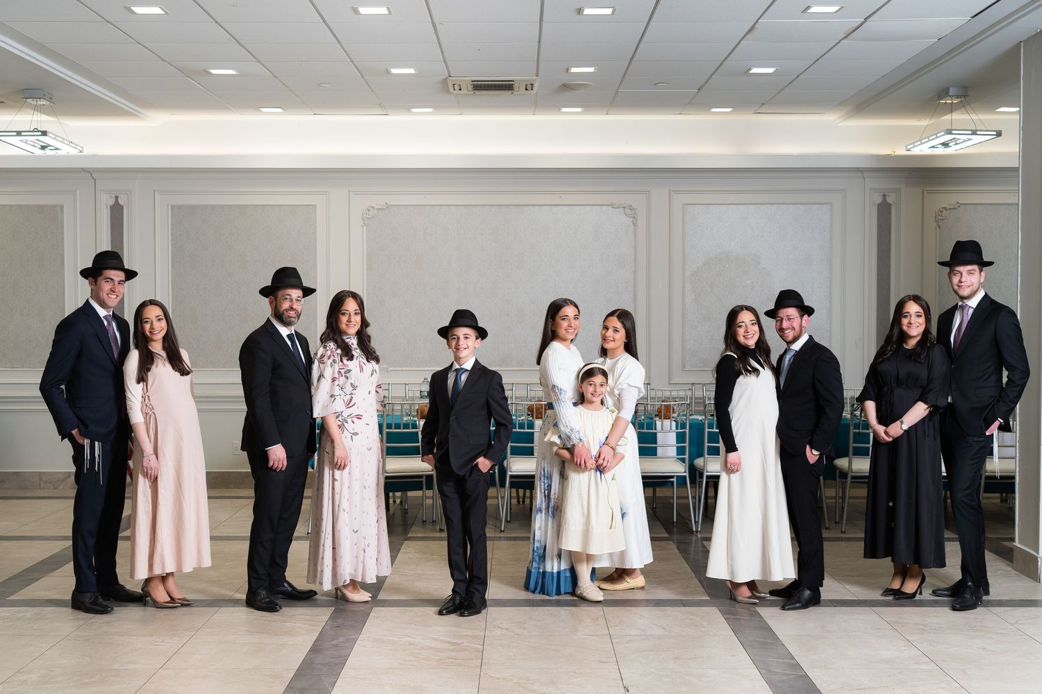 Formal family portrait of eleven people in elegant attire posing together in a banquet hall.