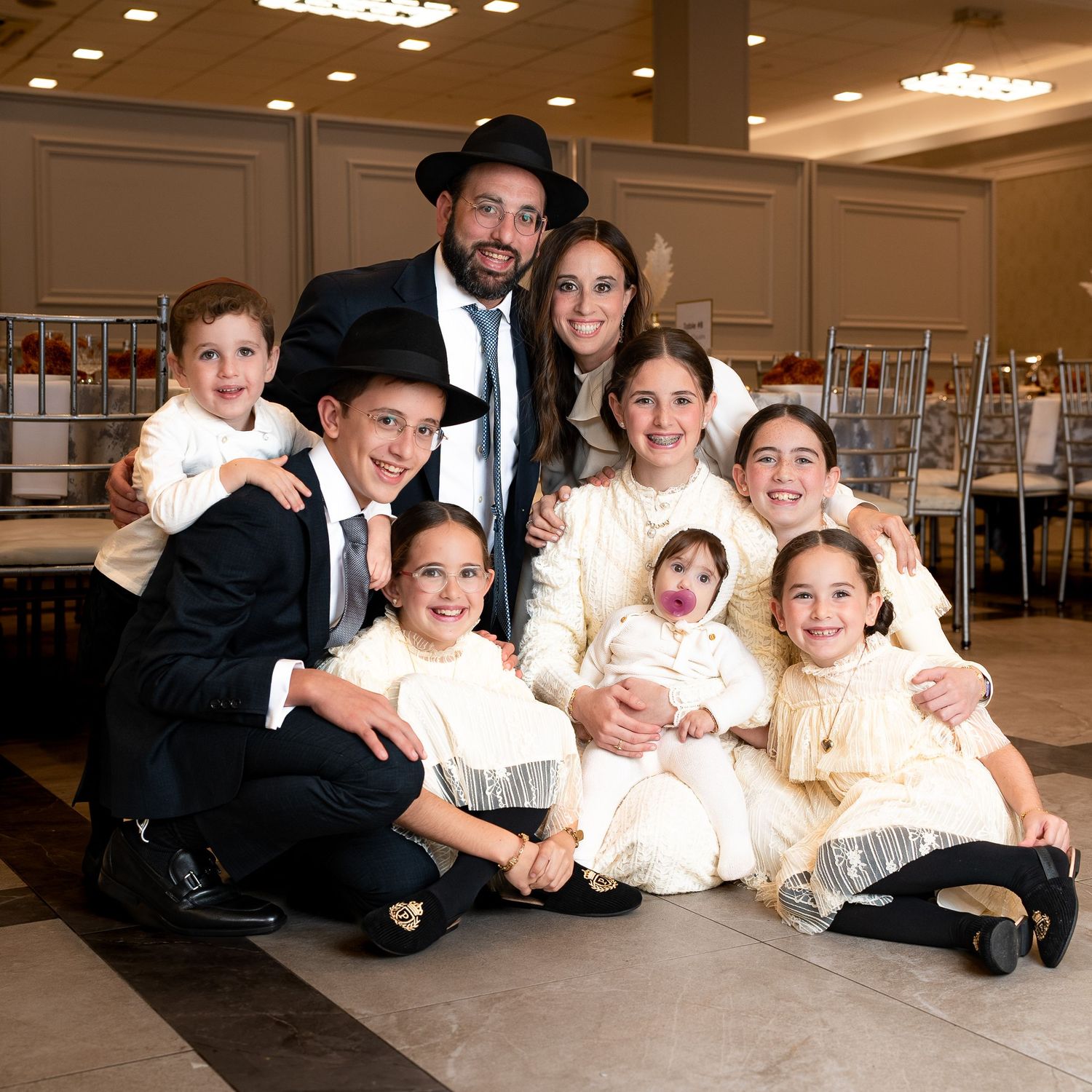 A large family portrait with adults and children in formal attire posed together indoors.
