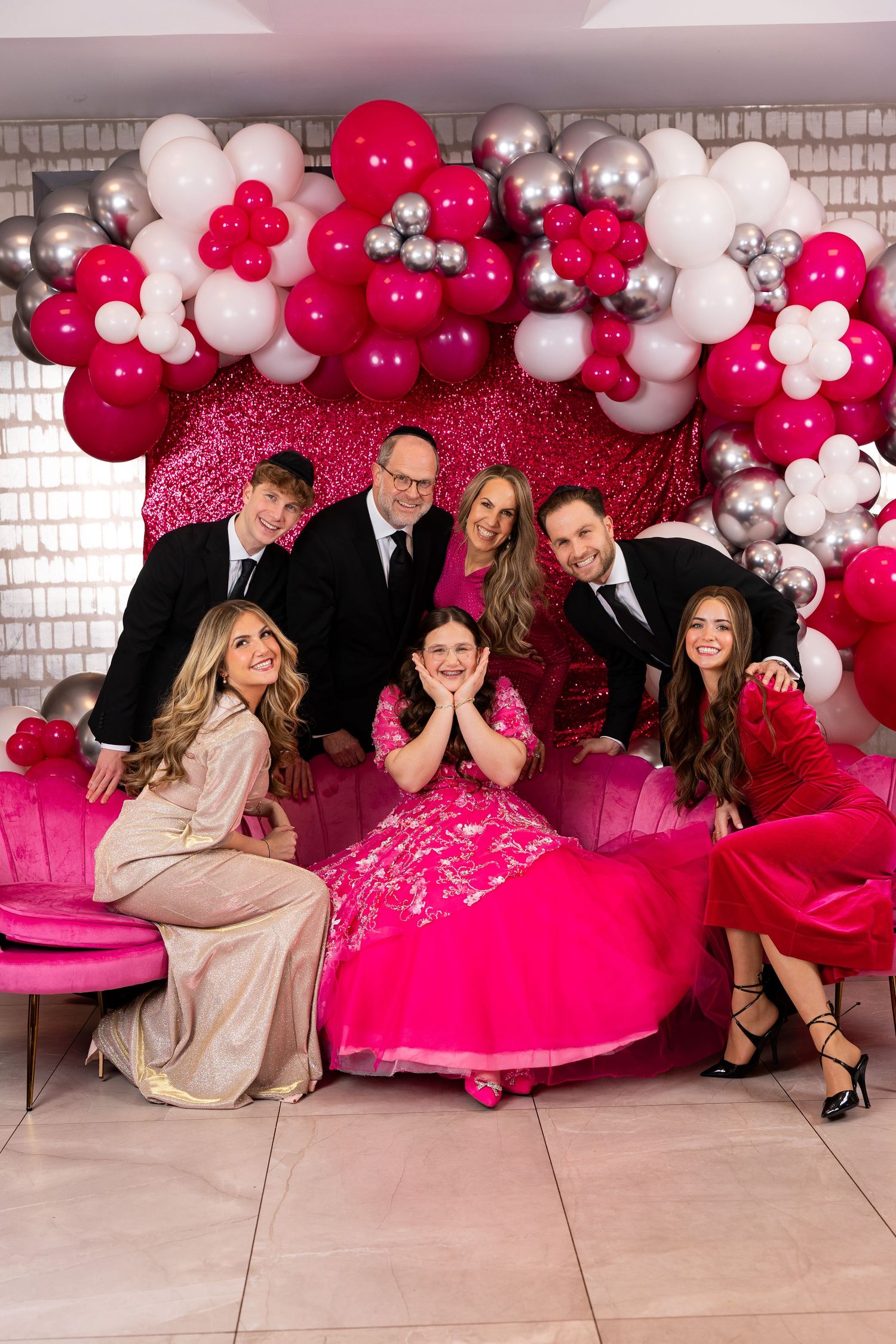 Party scene with vibrant pink and white balloon arch and decorative backdrop for celebration photos.