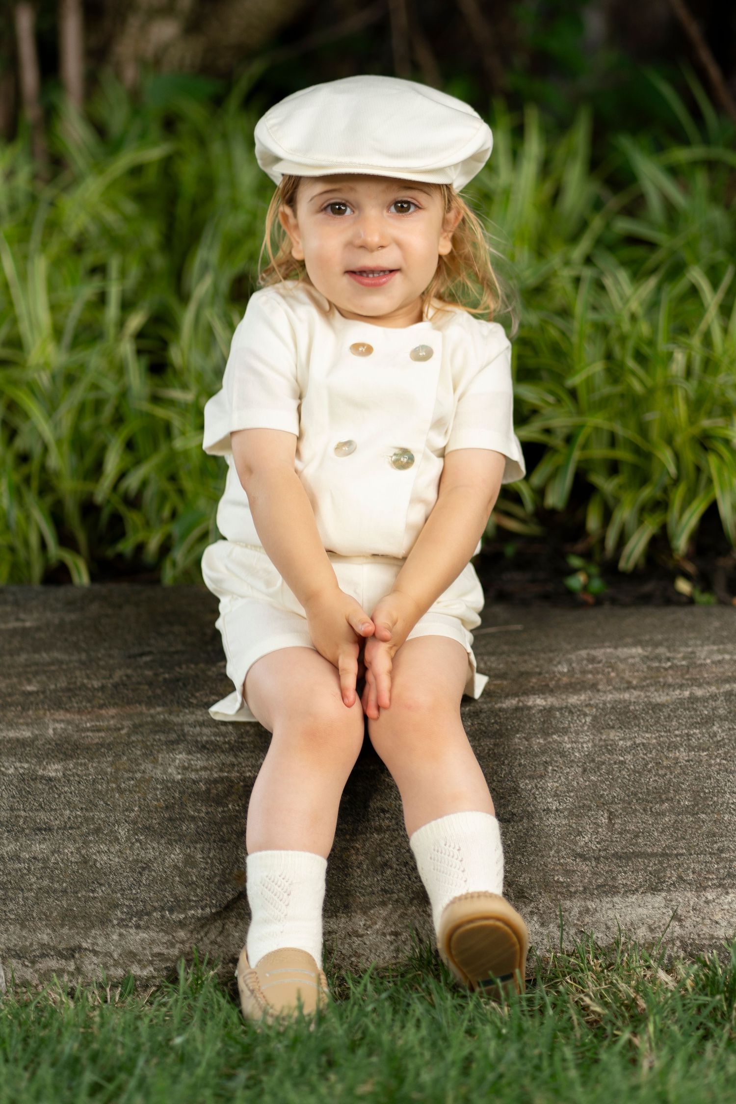 A series of photos showing small feet in white shoes and socks sitting on a concrete ledge near grass.