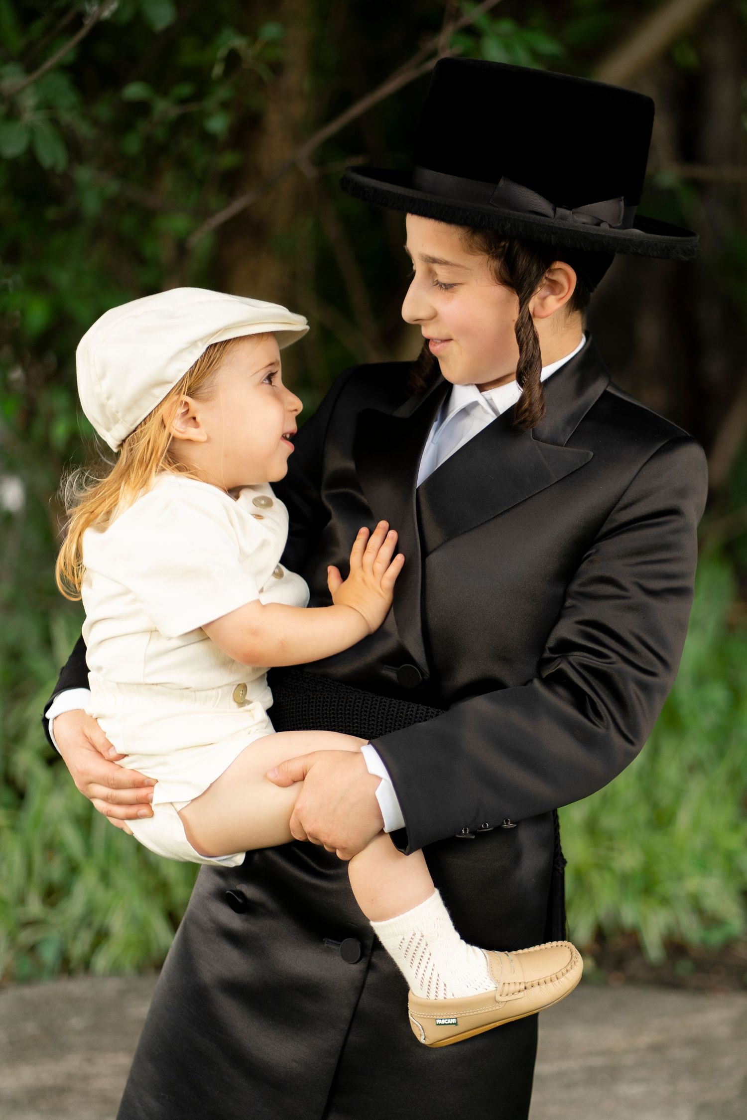 A tender moment between two people in traditional dress, one holding a small child in white.