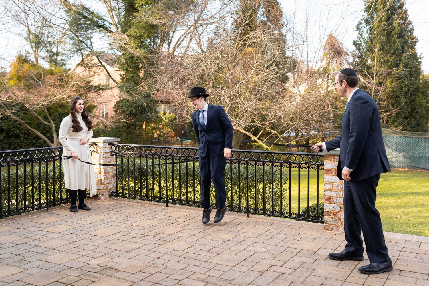 Wedding couple and guests dance together in a series of candid moments on an outdoor stone patio at sunset.