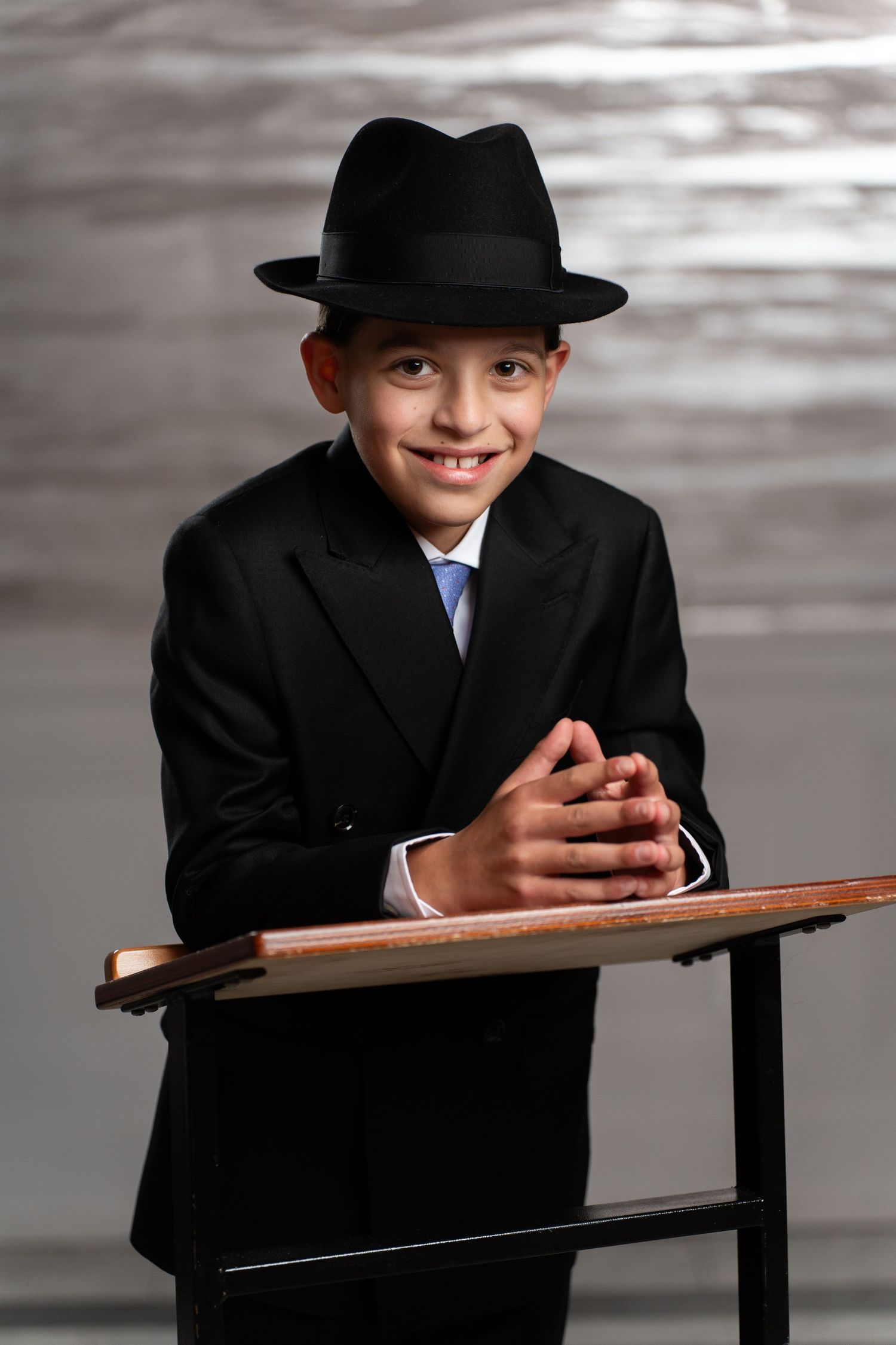 A series of four photos showing someone in a black suit and hat posing at different angles on a wooden bench.